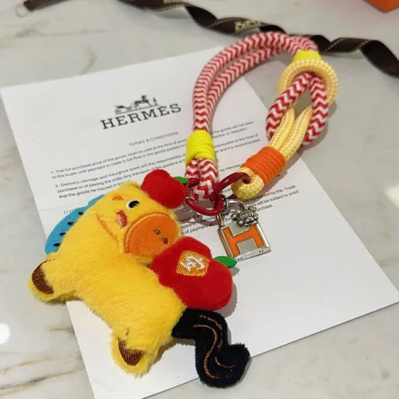 Hermes Cadenas H Lock Plush Capybara Charm pendant Silver-tone metal with orange enamel multicolor woven cord yellow plush with red blue orange black accents 18cm total strap length