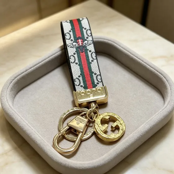 Gucci Anger Forest Bee Web GG Keychain pendant Gold-tone metal beige GG Supreme canvas with red and green web stripe brown leather backing multicolor bee motif 10cm strap length