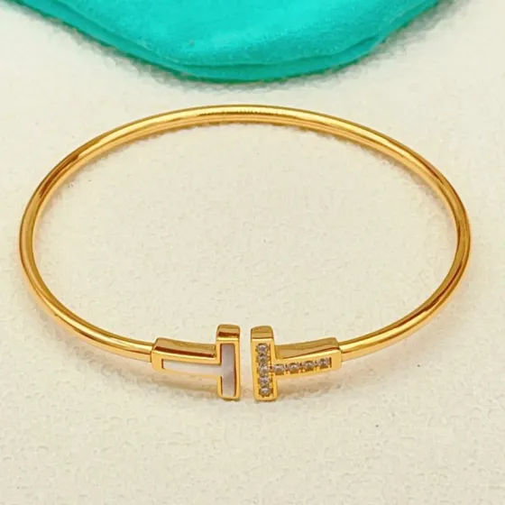 Tiffany Co T Wire bracelet yellow gold metal with white mother-of-pearl and clear diamond accents 17cm inner circumference