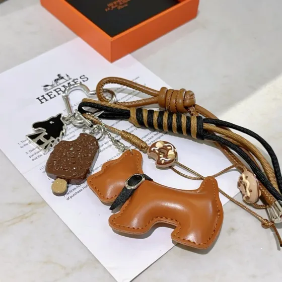 Hermes Buddy Scottie Dog Charm Keychain pendant Gold tan leather silver-tone metal black enamel brown and beige dessert-themed charms black and tan woven cord 15cm total strap length