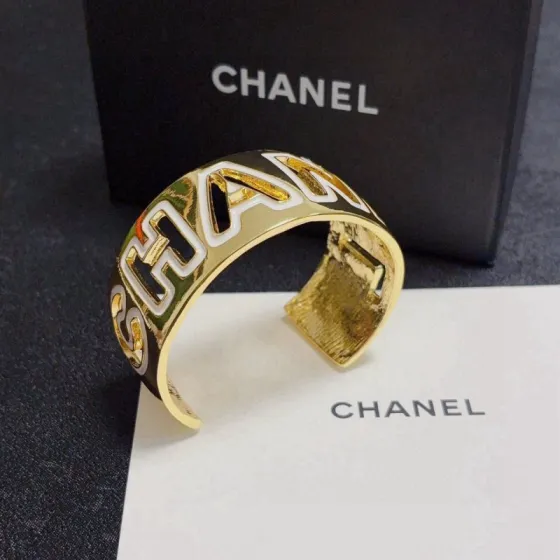 Chanel CHANEL Logo Cutout Wide Cuff bracelet Gold-tone metal with white enamel outlined cutout CHANEL lettering One Size adjustable open cuff fits 15-18cm wrist circumference