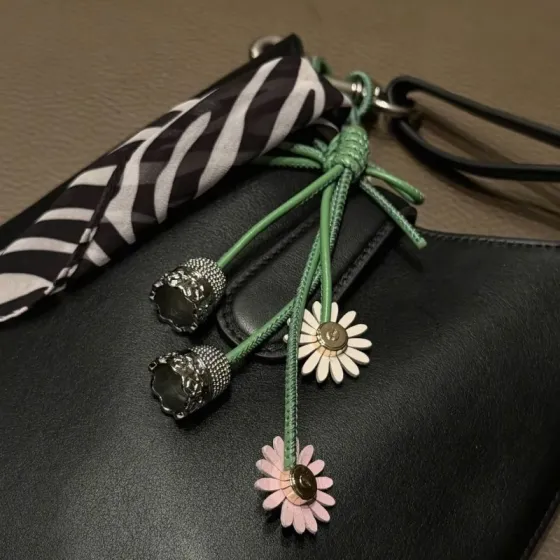 Dior Daisy Bell Bag Charm pendant green leather cord silver-tone metal bells cream and pink daisy accents with gold-tone centers 18cm total length