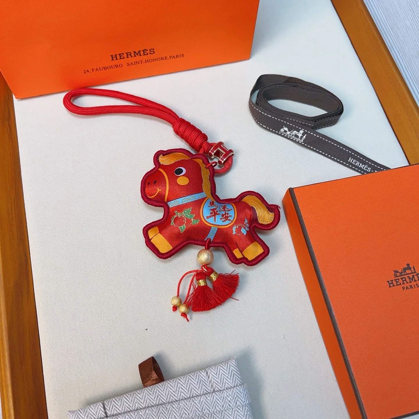 Ciondolo Hermes Anno del cavallo Lucky Nappa Tessuto rosso con dettagli decorativi oro blu verde cinturino in cordino rosso hardware in metallo color oro nappe rosse lunghezza totale 12 cm