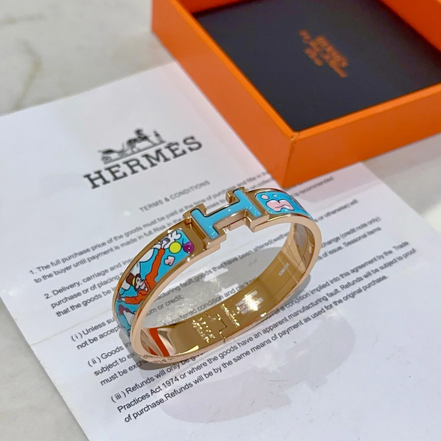 Bracciale Hermes Clic Clac H Metallo placcato oro rosa con smalto azzurro con stampa cartoon multicolor PM