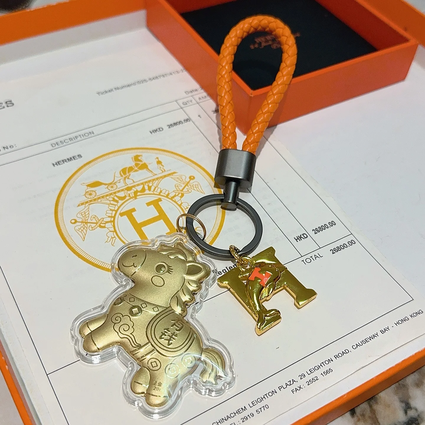 Hermes Lucky Horse H Logo Portachiavi Ciondolo con ciondolo Pelle intrecciata arancione Hardware in canna di fucile Ciondoli in metallo color oro con accento H arancione Rivestimento in acrilico trasparente 10 cm Cinturino intrecciato 4 cm