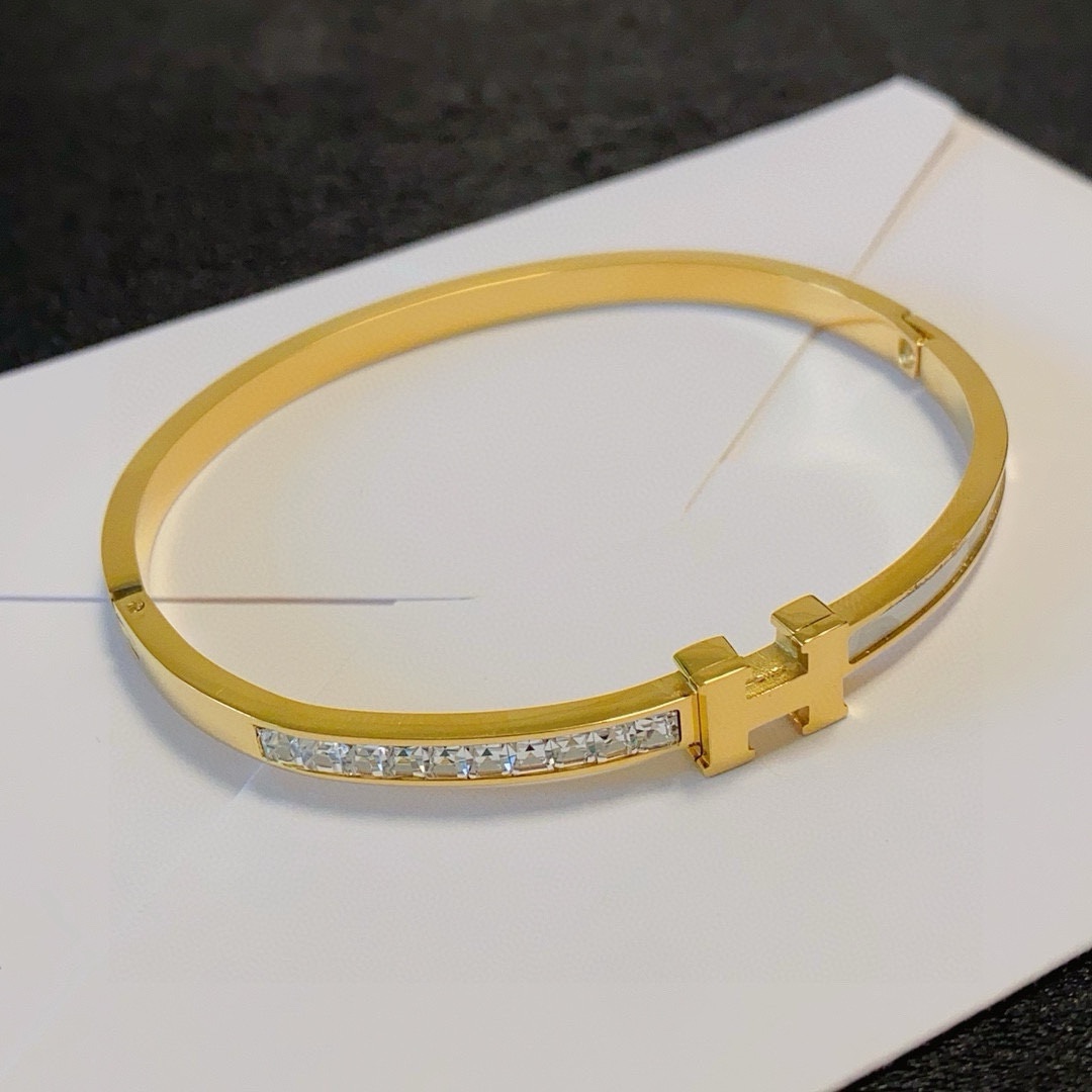 Bracciale Hermes Clic H MM in metallo color oro con cristalli trasparenti e smalto bianco