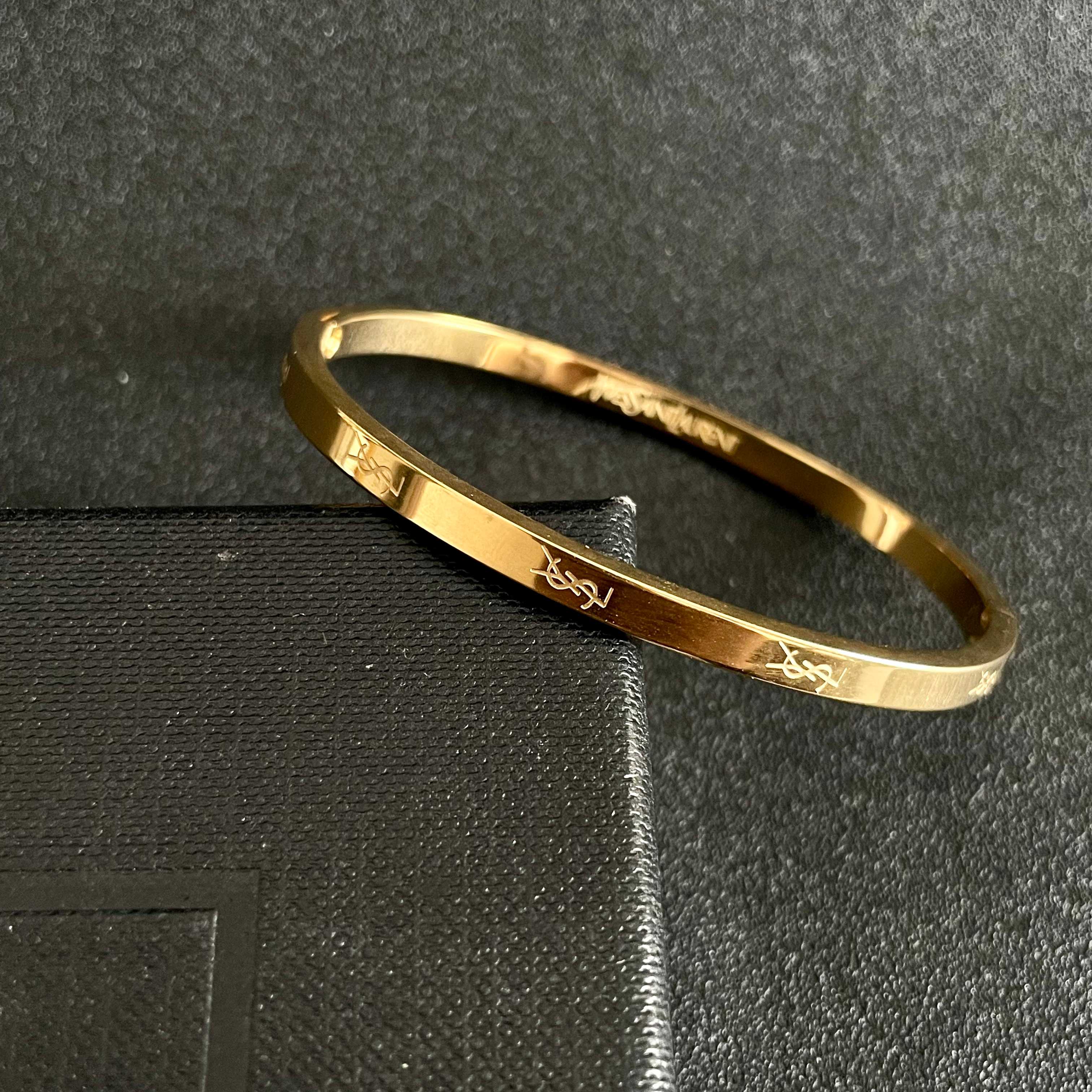 Saint Laurent Cassandre Logo Engraved Hinged Bangle bracelet 18K gold tone metal no accent stones 17cm inner circumference