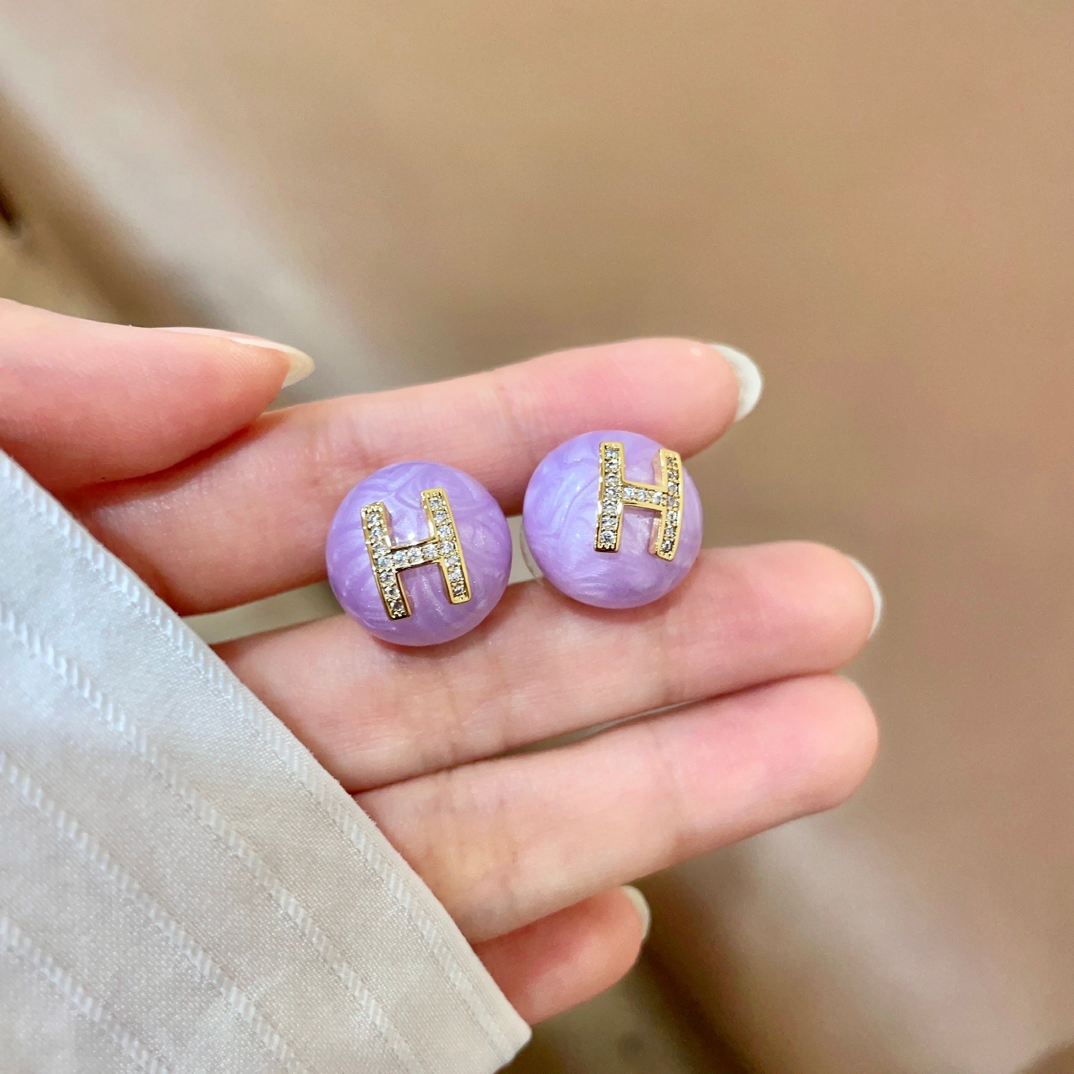 Orecchini Hermes H Logo Orecchini base in resina viola lavanda con logo H in metallo color oro incastonato con cristalli trasparenti diametro 1 2 cm