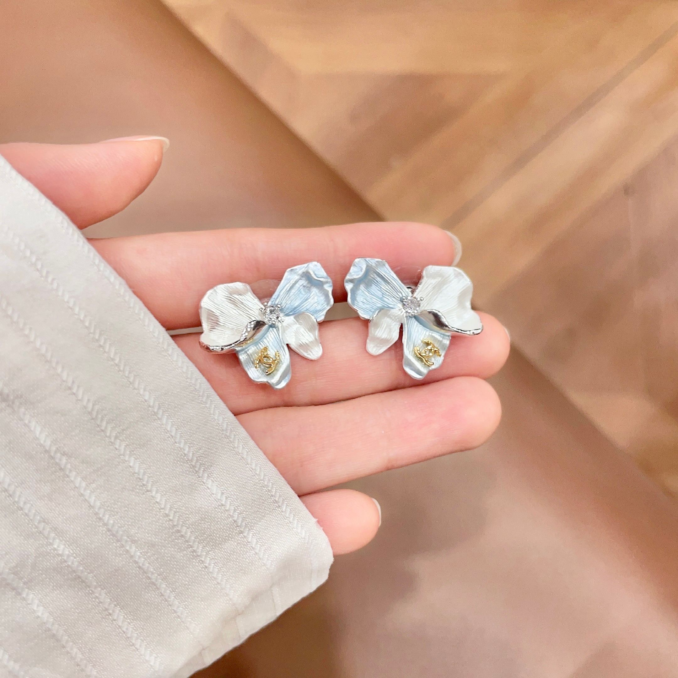 Chanel CC Logo Iridescent Flower Stud Earrings earrings Silver-toned metal with iridescent pearlescent white pale blue pale yellow pale purple or pale peach enamel petals gold-tone interlocking CC logo clear crystal accent One Size 2cm width per earring