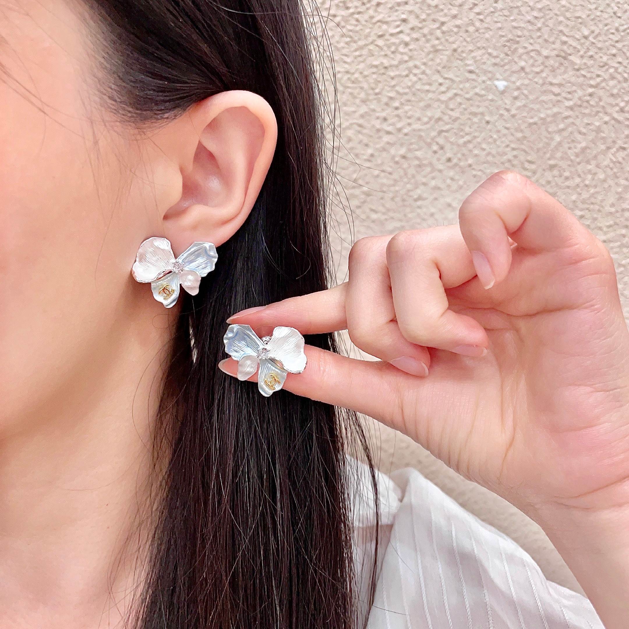 Chanel CC Logo Iridescent Flower Stud Earrings earrings Silver-toned metal with iridescent pearlescent white pale blue pale yellow pale purple or pale peach enamel petals gold-tone interlocking CC logo clear crystal accent One Size 2cm width per earring