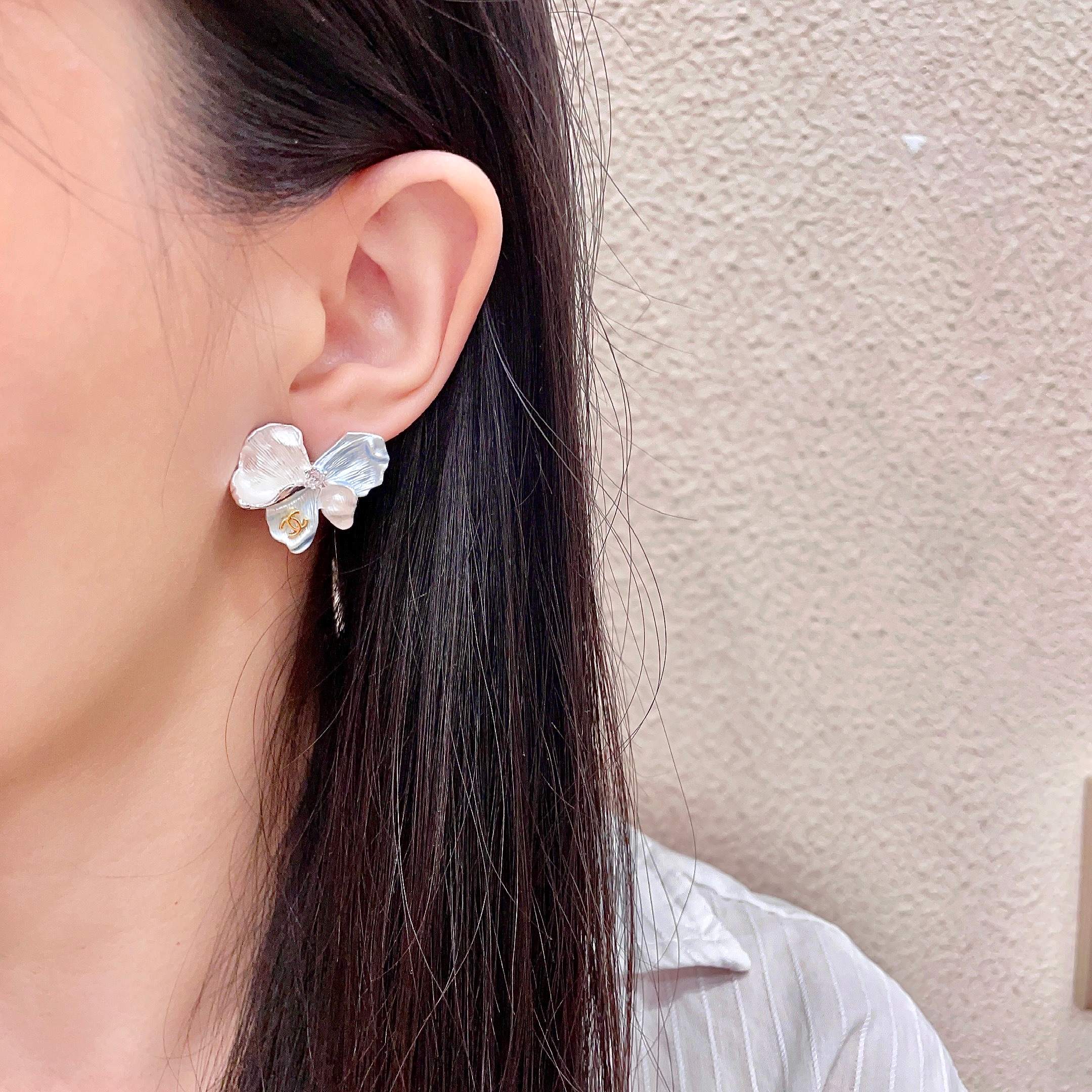 Chanel CC Logo Iridescent Flower Stud Earrings earrings Silver-toned metal with iridescent pearlescent white pale blue pale yellow pale purple or pale peach enamel petals gold-tone interlocking CC logo clear crystal accent One Size 2cm width per earring