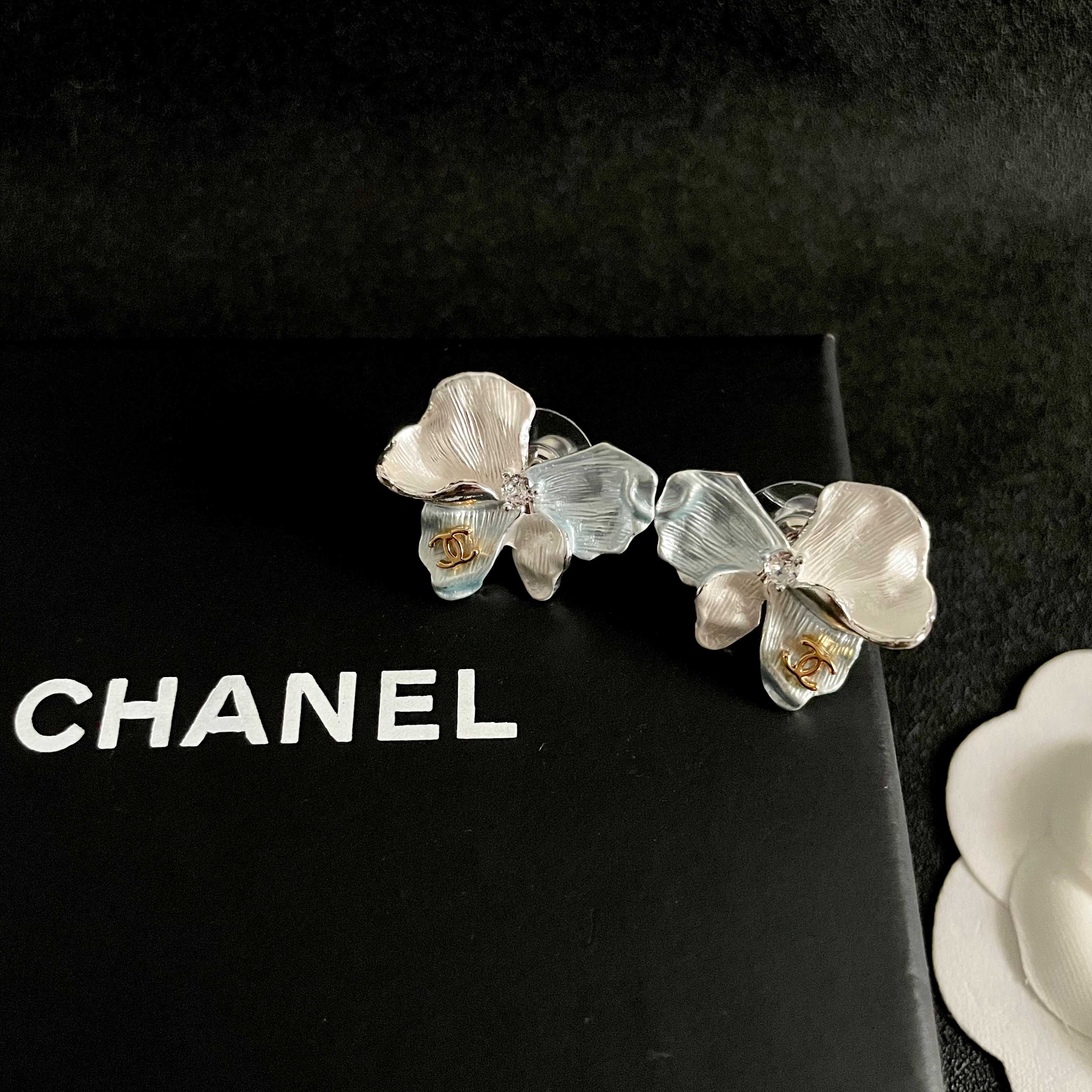 Chanel CC Logo Iridescent Flower Stud Earrings earrings Silver-toned metal with iridescent pearlescent white pale blue pale yellow pale purple or pale peach enamel petals gold-tone interlocking CC logo clear crystal accent One Size 2cm width per earring