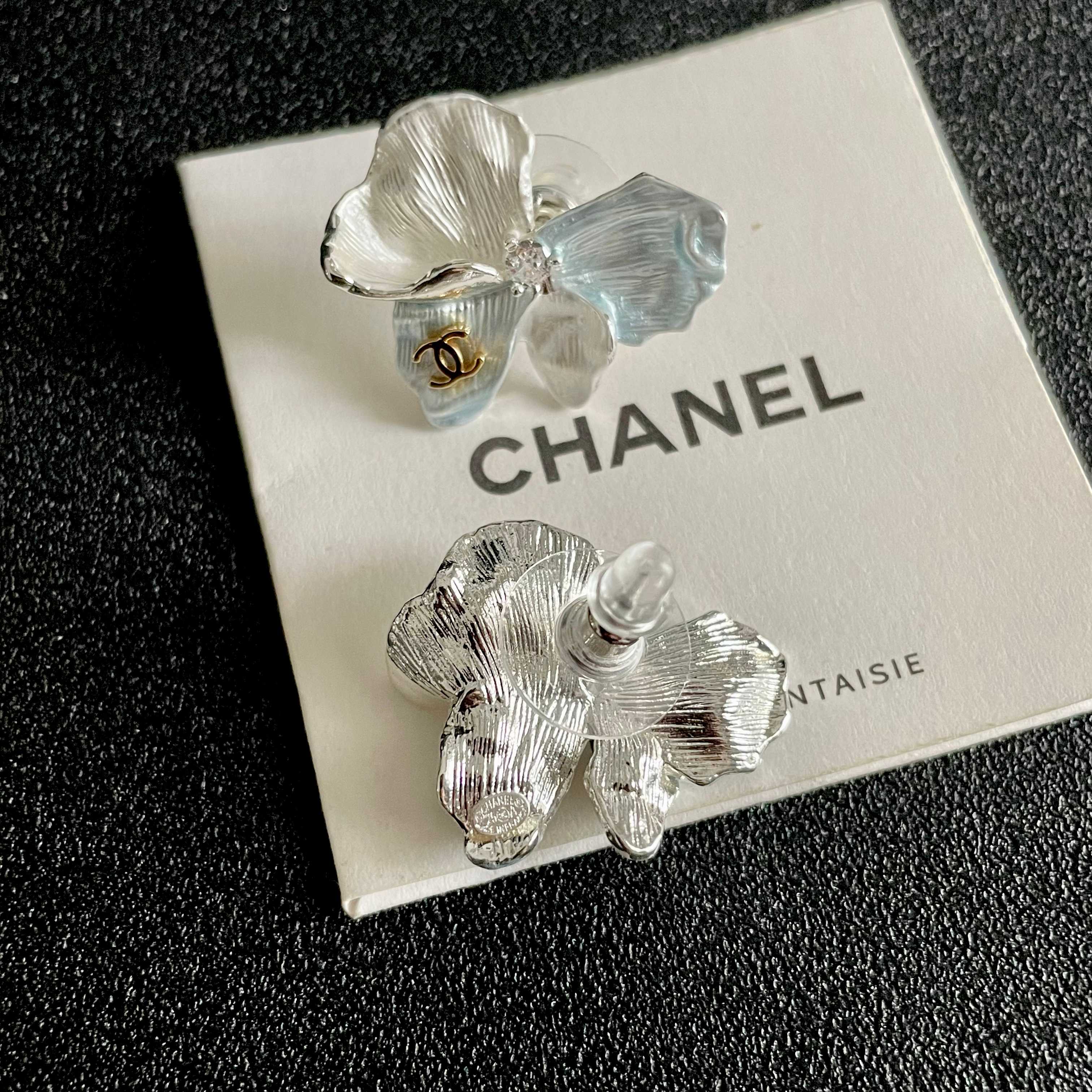 Chanel CC Logo Iridescent Flower Stud Earrings earrings Silver-toned metal with iridescent pearlescent white pale blue pale yellow pale purple or pale peach enamel petals gold-tone interlocking CC logo clear crystal accent One Size 2cm width per earring