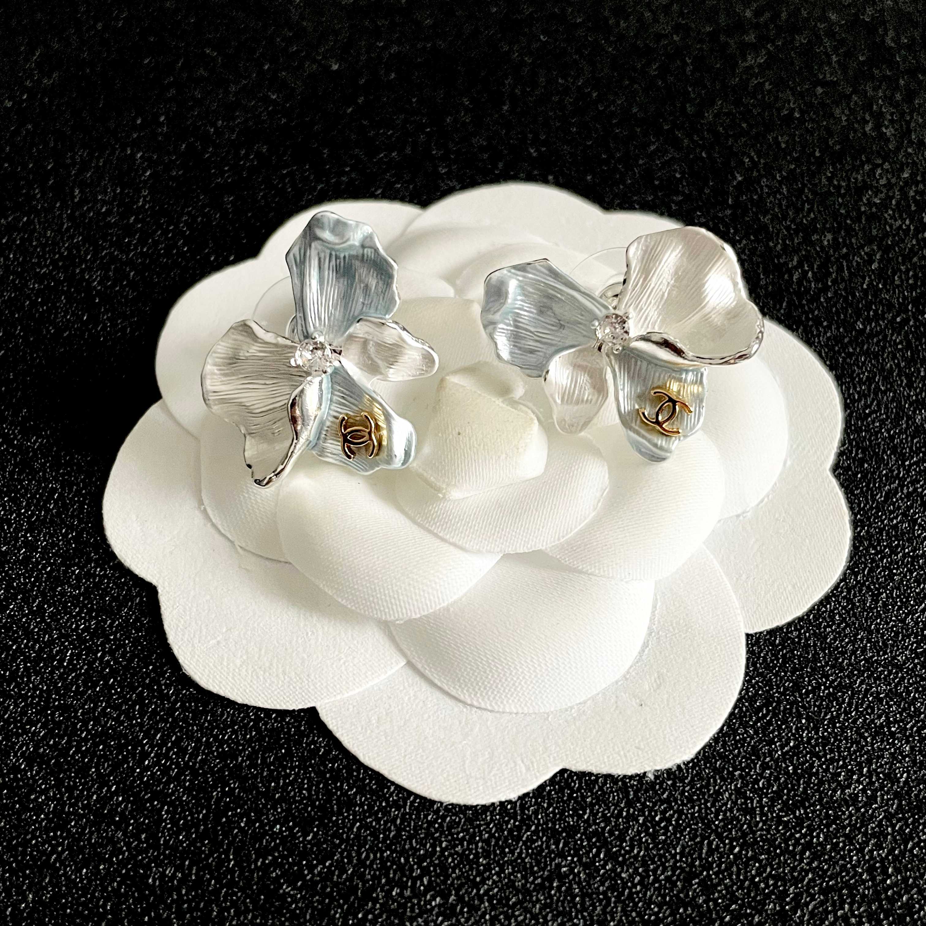 Chanel CC Logo Iridescent Flower Stud Earrings earrings Silver-toned metal with iridescent pearlescent white pale blue pale yellow pale purple or pale peach enamel petals gold-tone interlocking CC logo clear crystal accent One Size 2cm width per earring