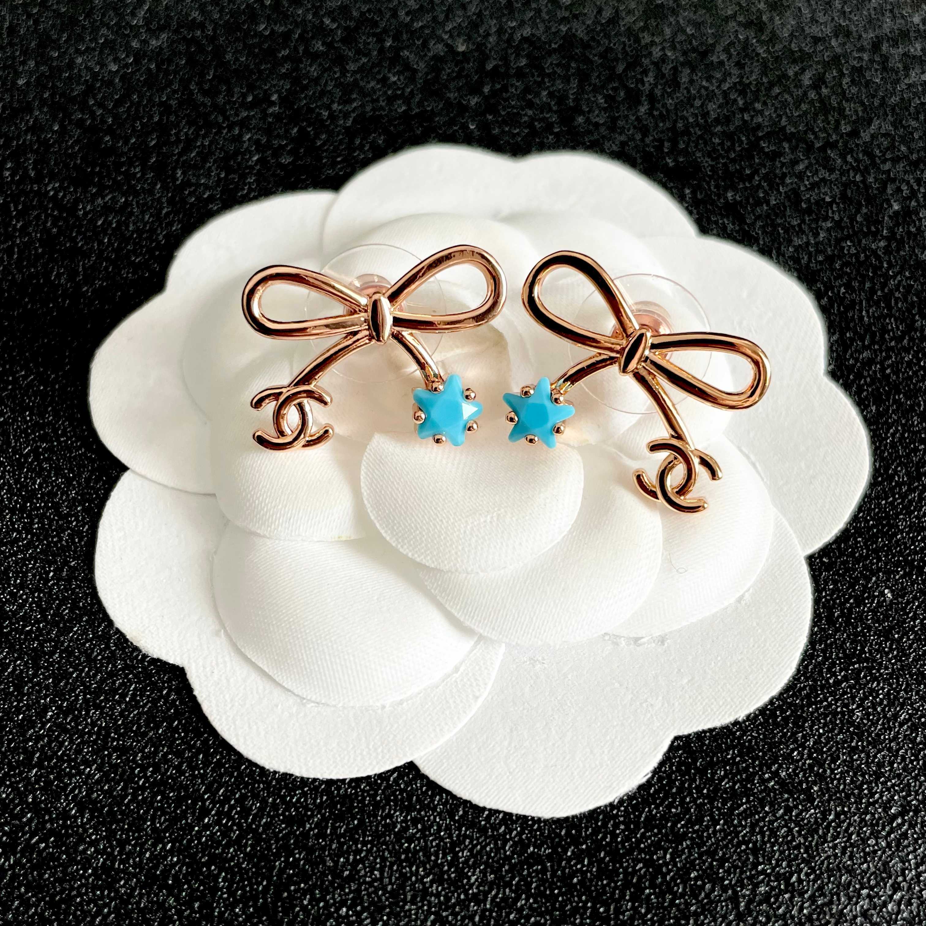 Chanel CC Bow Star Charm Stud Earrings earrings Rose gold light gold tone metal with clear crystal or turquoise blue star accents One Size standard stud earring dimensions approx 1 5cm width