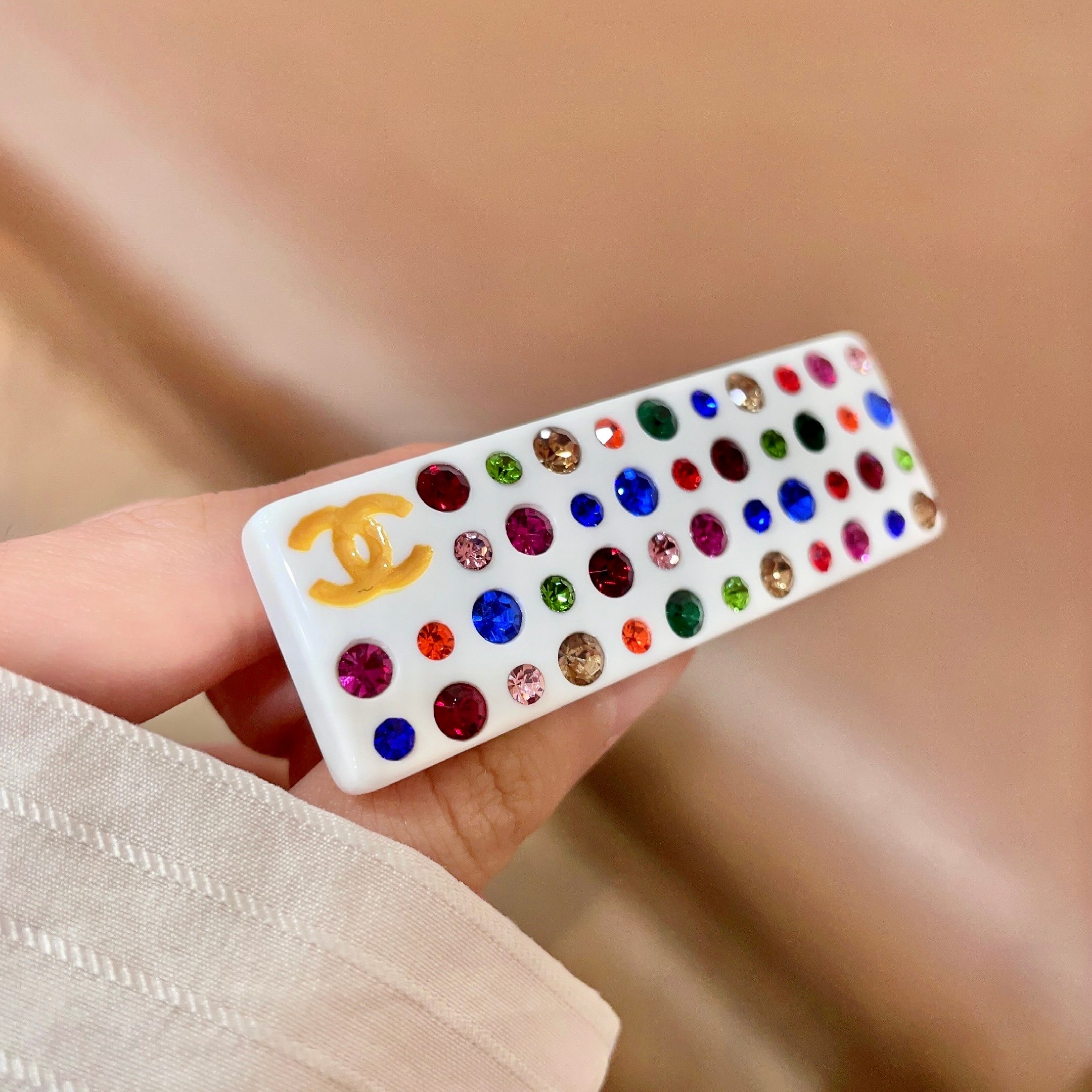 Chanel CC Logo Multicolor Crystal Resin Hair Barrette brooch White resin base with gold-tone interlocking CC logo multicolor faceted crystals in red blue green pink orange champagne and light pink hues 8cm length