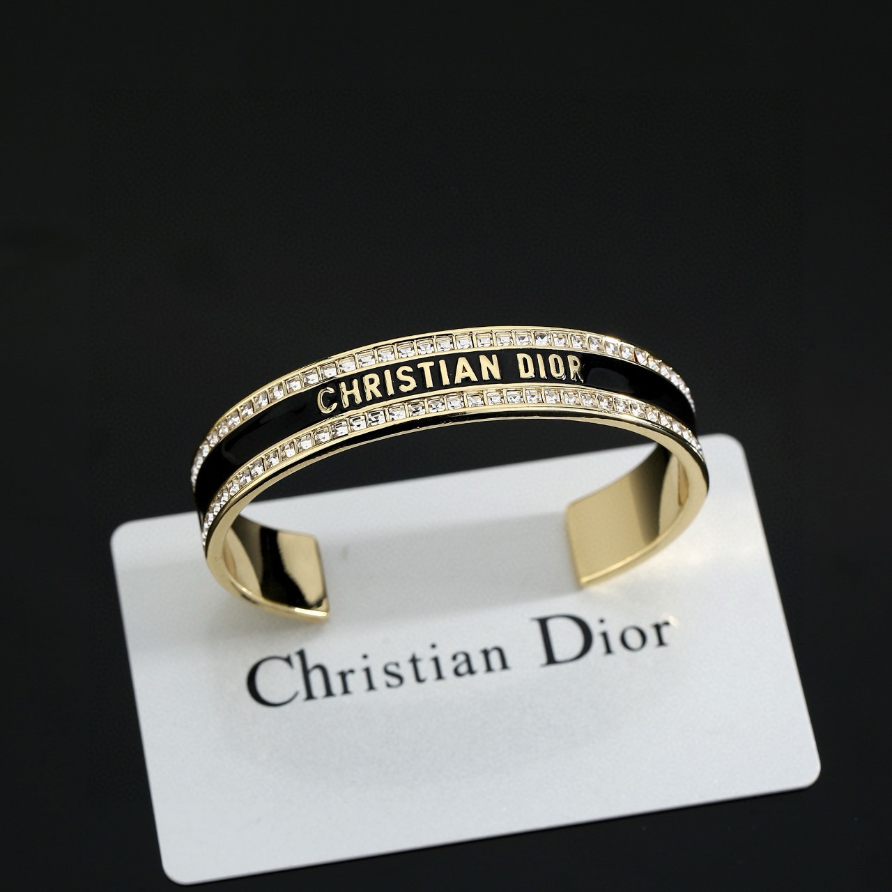 Dior Christian Dior Night Code Cuff bracelet Gold-tone metal with clear crystal accents available with black or white enamel inlay 17cm inner circumference
