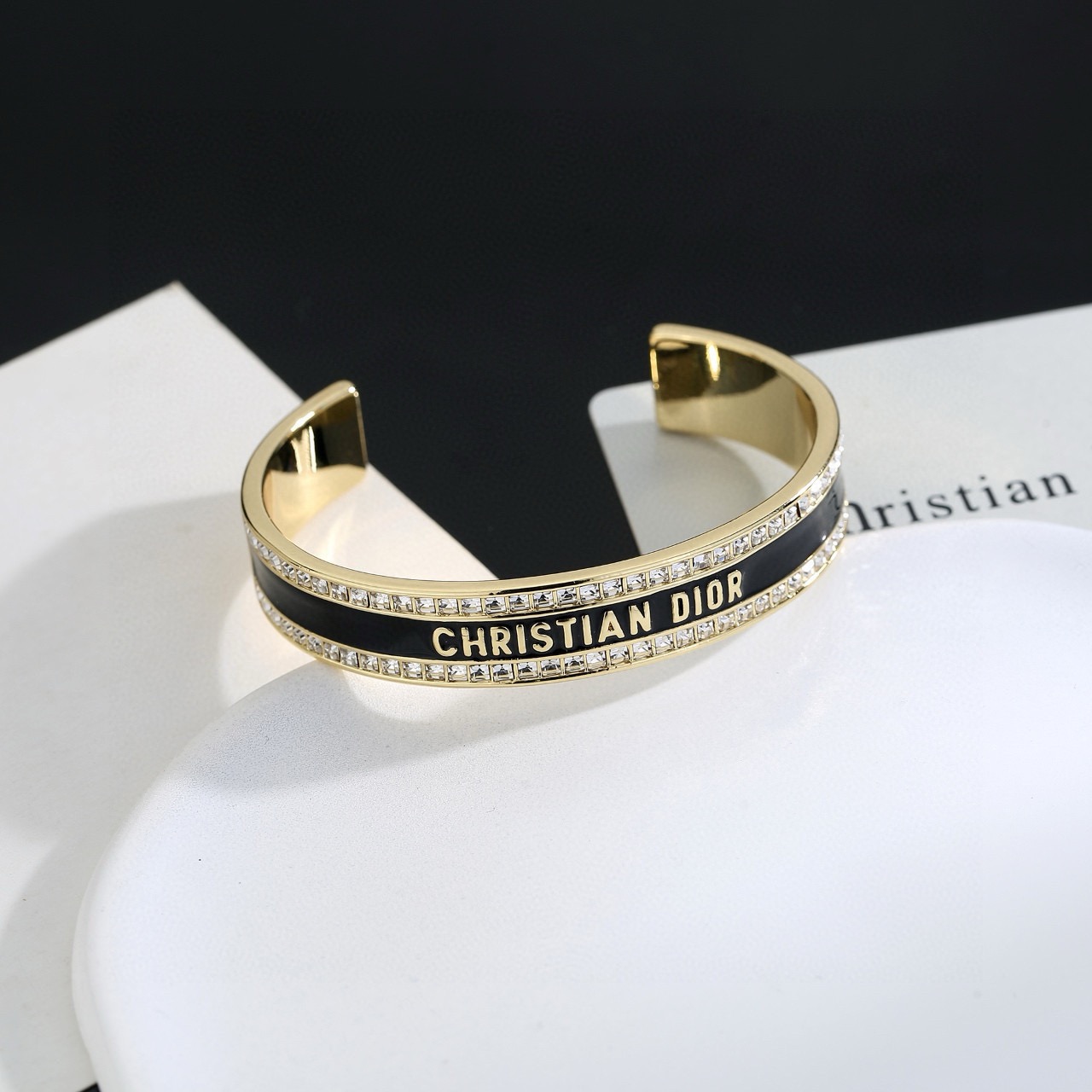 Dior Christian Dior Night Code Cuff bracelet Gold-tone metal with clear crystal accents available with black or white enamel inlay 17cm inner circumference