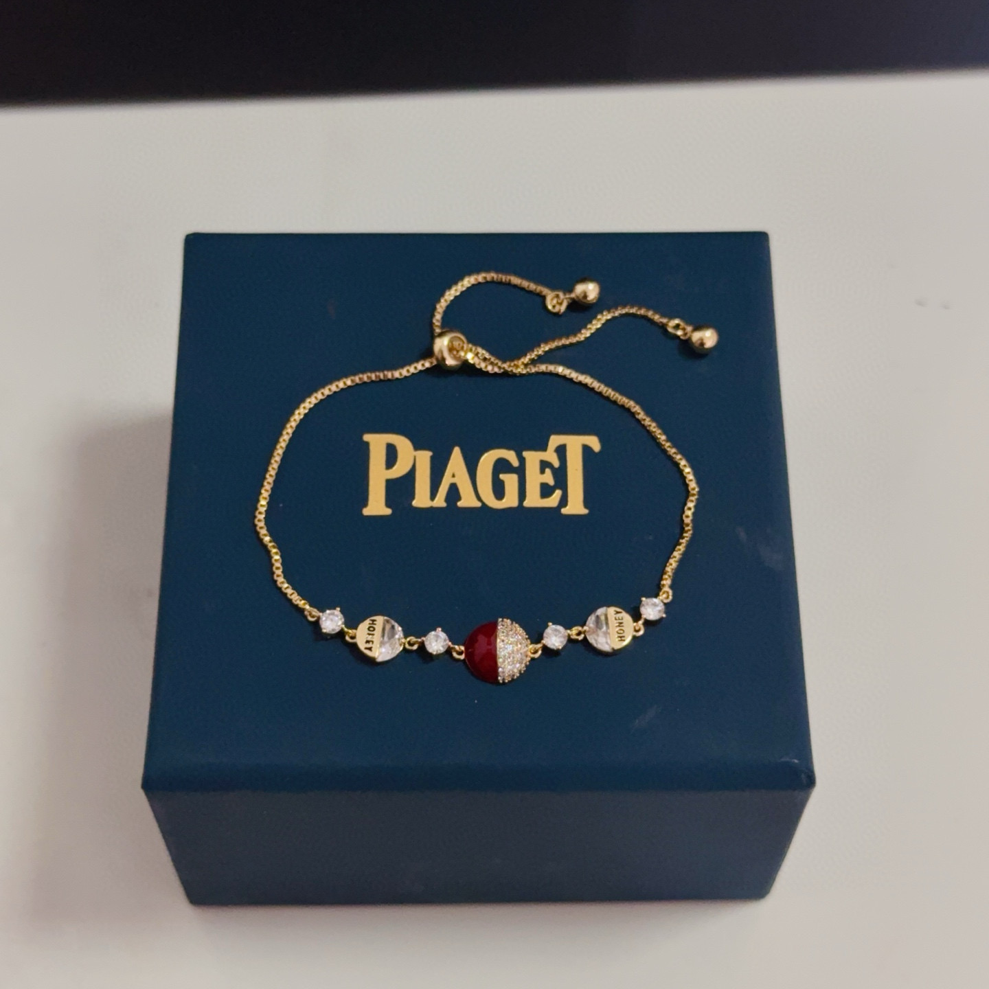 Piaget Possession bracelet yellow gold metal clear diamond-like crystals deep red enamel accent adjustable sliding chain 16-20cm