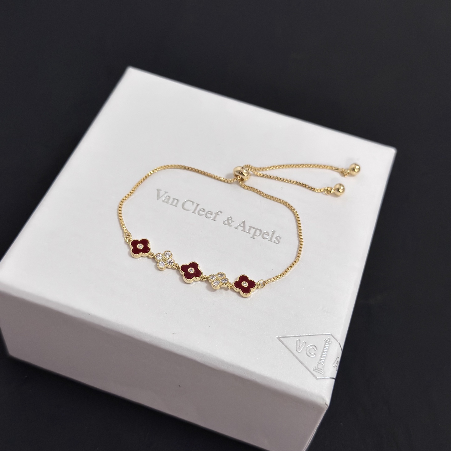 Van Cleef Arpels Alhambra bracelet yellow gold metal burgundy carnelian clover inlays clear diamond accents adjustable sliding chain maximum length 22cm