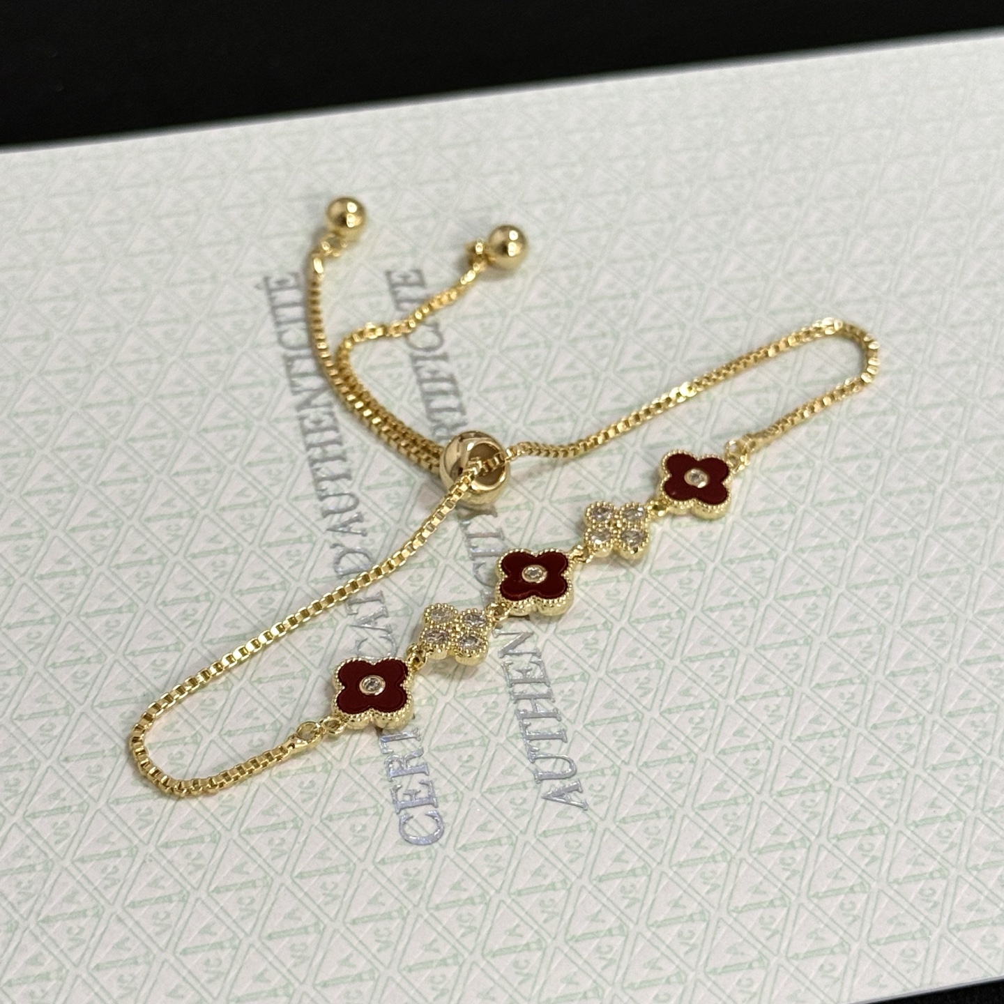 Van Cleef Arpels Alhambra bracelet yellow gold metal burgundy carnelian clover inlays clear diamond accents adjustable sliding chain maximum length 22cm