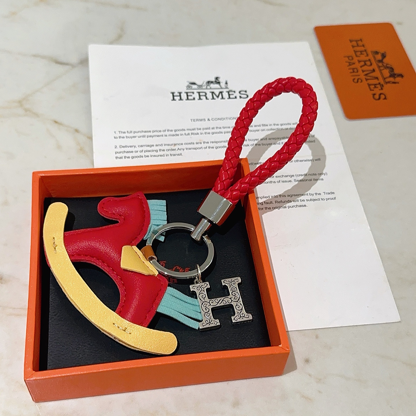 Hermes Rocking Horse H Charm Llavero colgante Cuero trenzado rojo metal plateado cuero multicolor rojo amarillo azul claro Correa trenzada de 10 cm