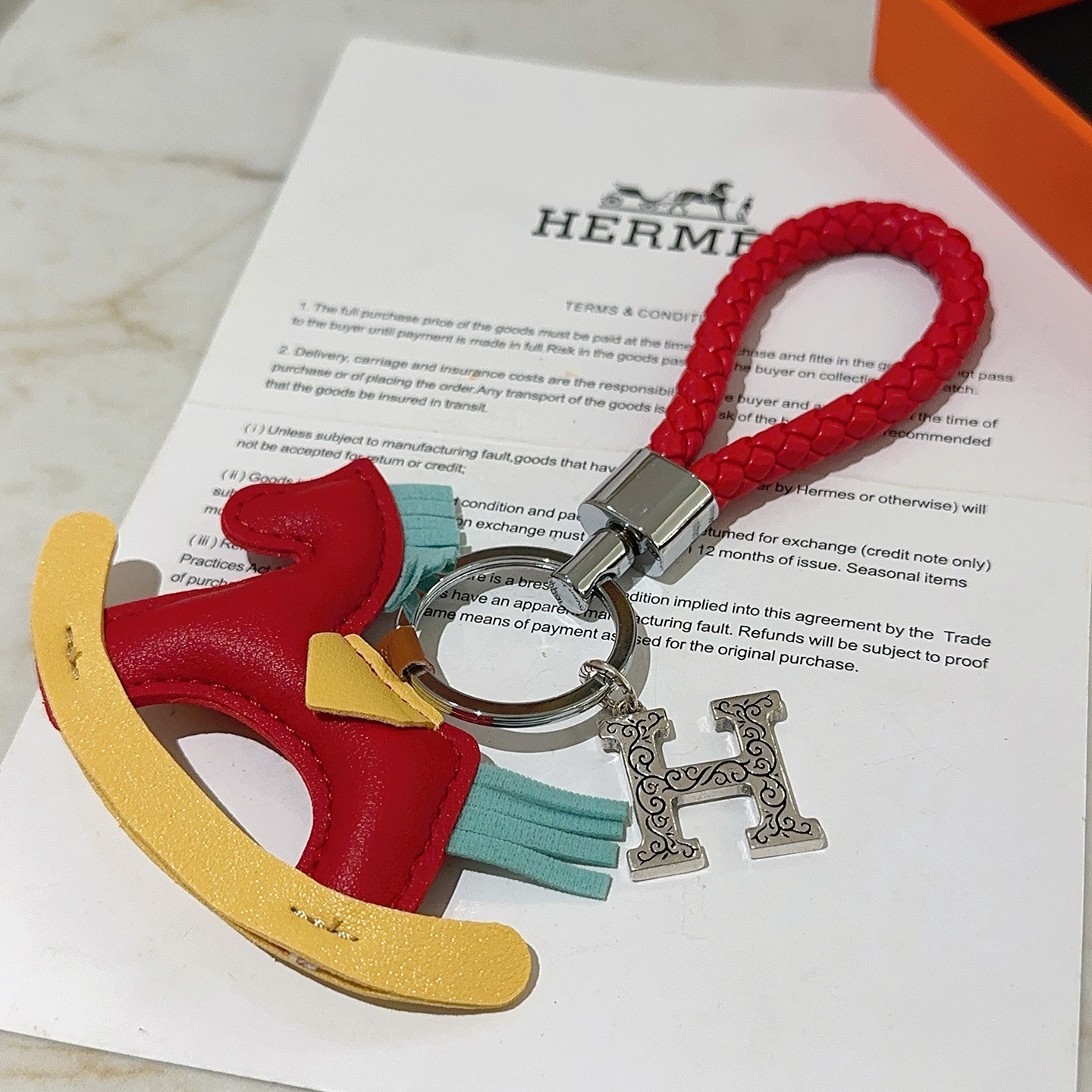 Hermes Rocking Horse H Charm Llavero colgante Cuero trenzado rojo metal plateado cuero multicolor rojo amarillo azul claro Correa trenzada de 10 cm