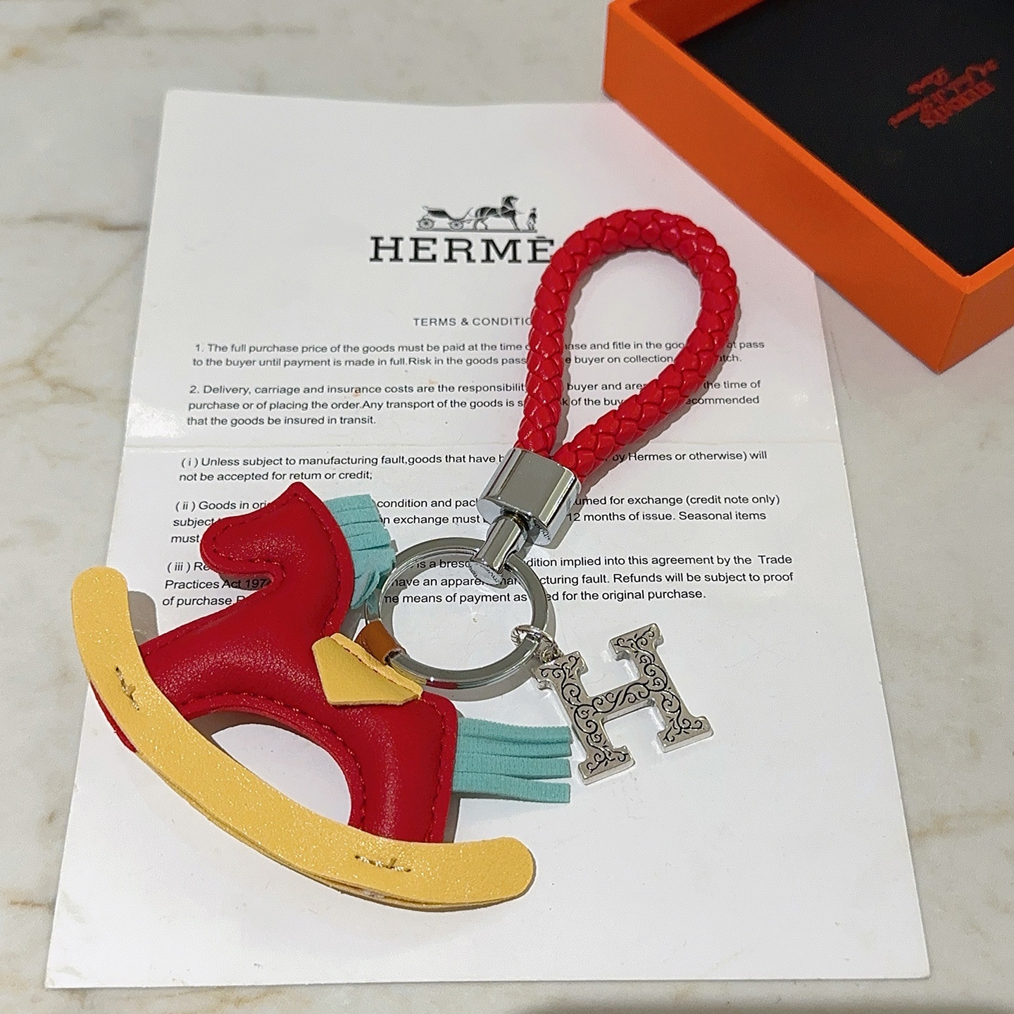 Hermes Rocking Horse H Charm Llavero colgante Cuero trenzado rojo metal plateado cuero multicolor rojo amarillo azul claro Correa trenzada de 10 cm