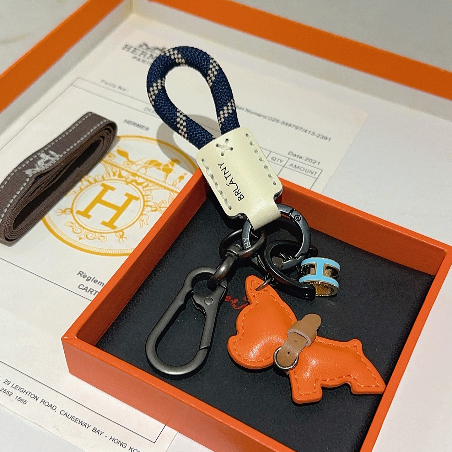 Hermes Pop H Dog Charm Portachiavi Ciondolo Hardware grigio canna di fucile Cavo intrecciato blu navy Accento in pelle color crema Ciondolo per cani in pelle arancione Dettaglio collare in pelle marrone Ciondolo H in smalto azzurro con finiture dorate Lunghezza totale 10 cm