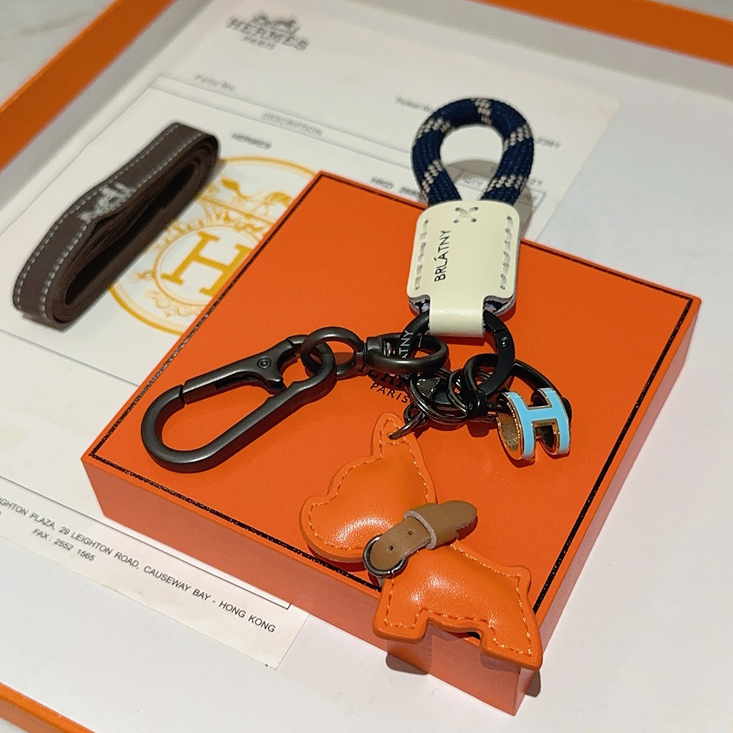 Hermes Pop H Dog Charm Portachiavi Ciondolo Hardware grigio canna di fucile Cavo intrecciato blu navy Accento in pelle color crema Ciondolo per cani in pelle arancione Dettaglio collare in pelle marrone Ciondolo H in smalto azzurro con finiture dorate Lunghezza totale 10 cm
