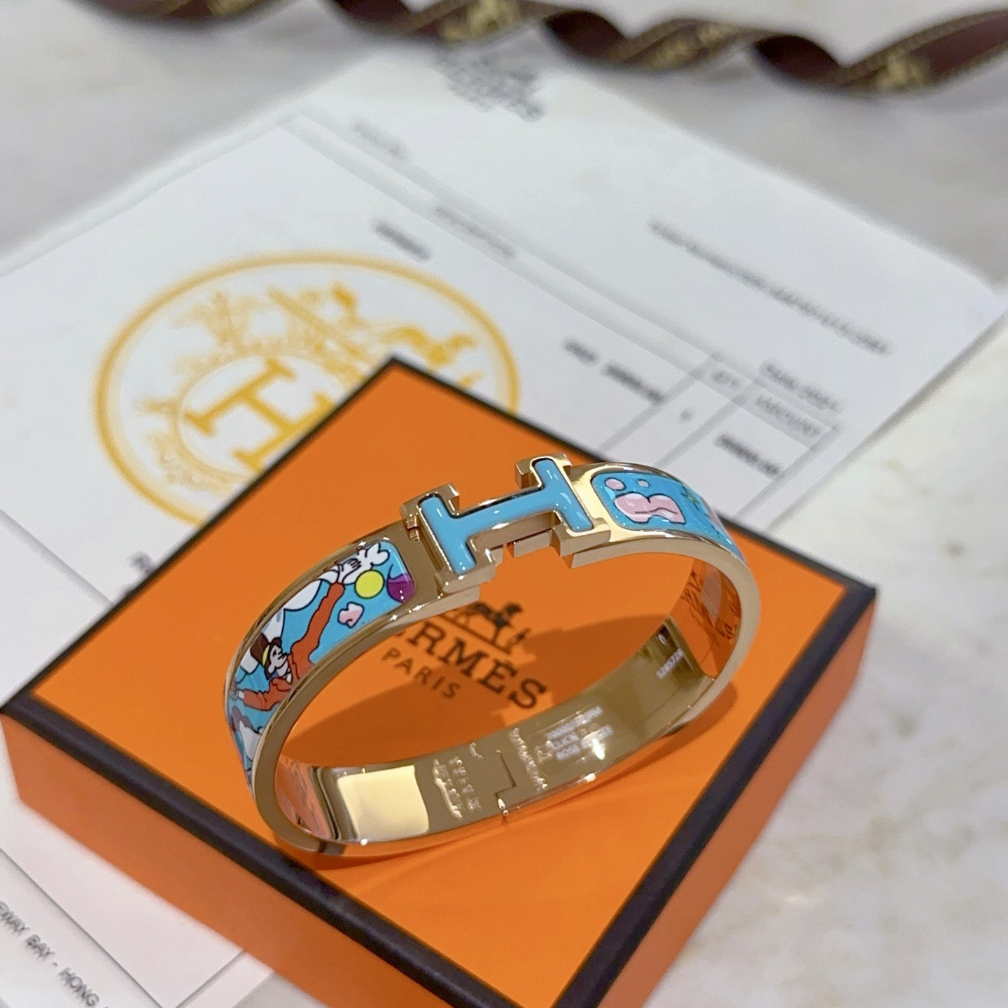 Bracciale Hermes Clic Clac H Metallo placcato oro rosa con smalto azzurro con stampa cartoon multicolor PM