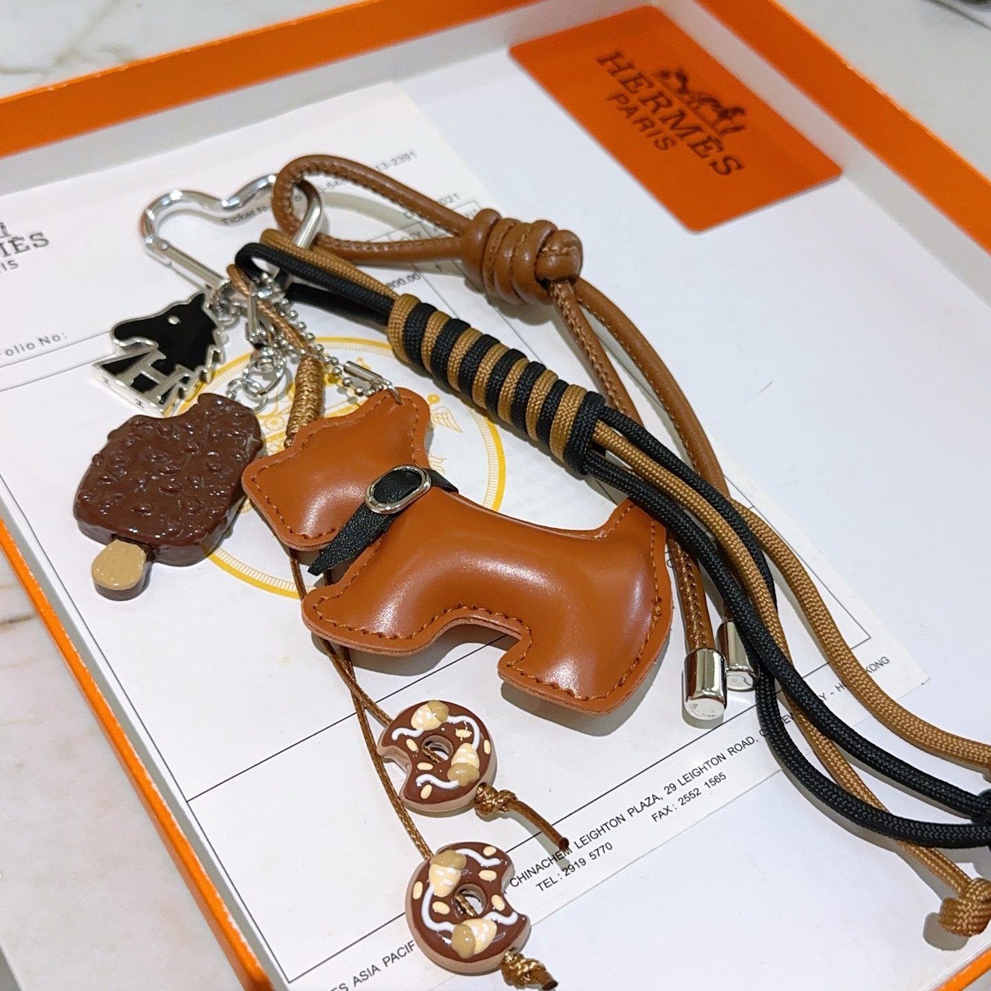 Ciondolo portachiavi Hermes Buddy Scottie Dog Charm Portachiavi in ​​pelle marrone chiaro dorata metallo argentato smalto nero ciondoli a tema dessert marrone e beige cordone intrecciato nero e marrone chiaro lunghezza totale del cinturino 15 cm