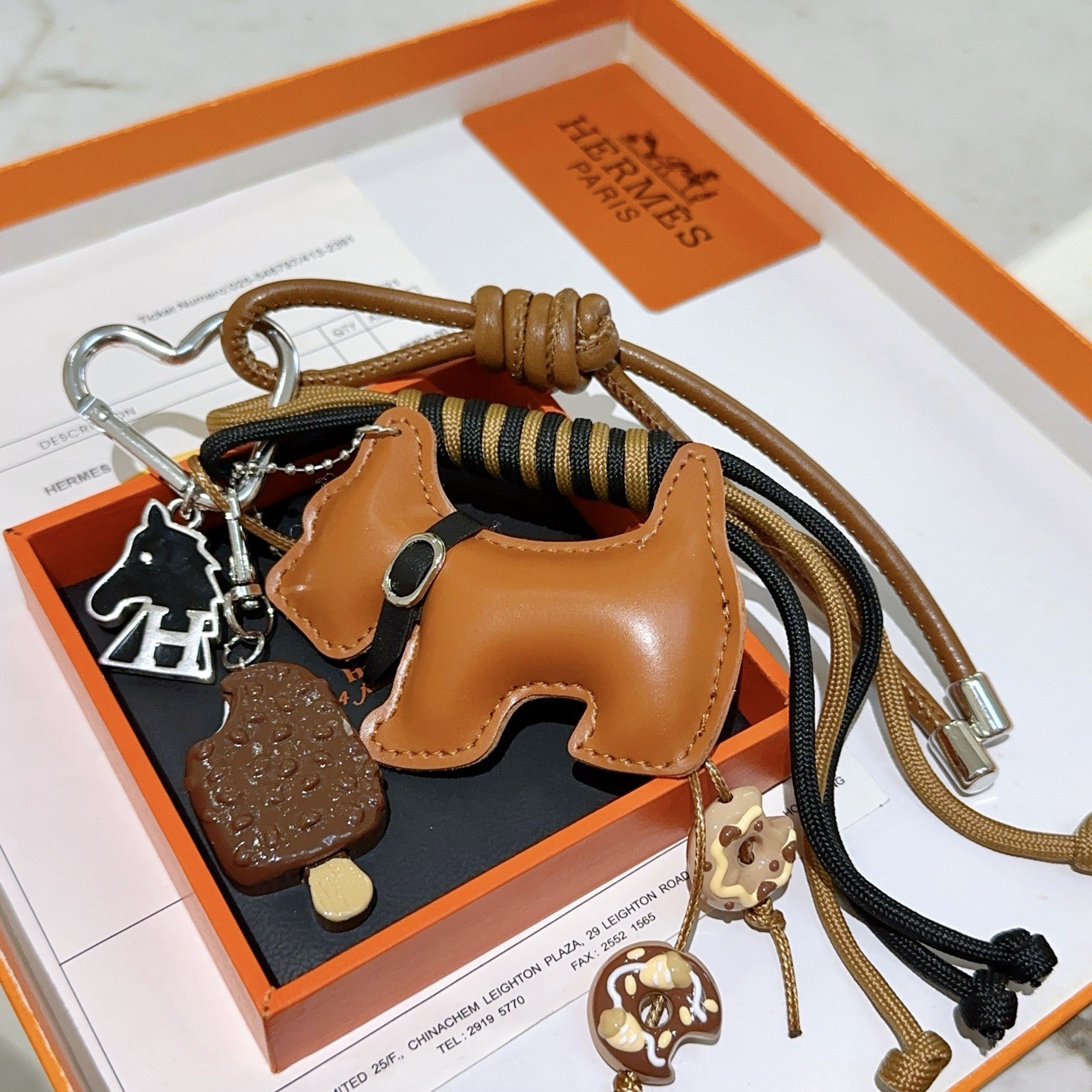 Ciondolo portachiavi Hermes Buddy Scottie Dog Charm Portachiavi in ​​pelle marrone chiaro dorata metallo argentato smalto nero ciondoli a tema dessert marrone e beige cordone intrecciato nero e marrone chiaro lunghezza totale del cinturino 15 cm