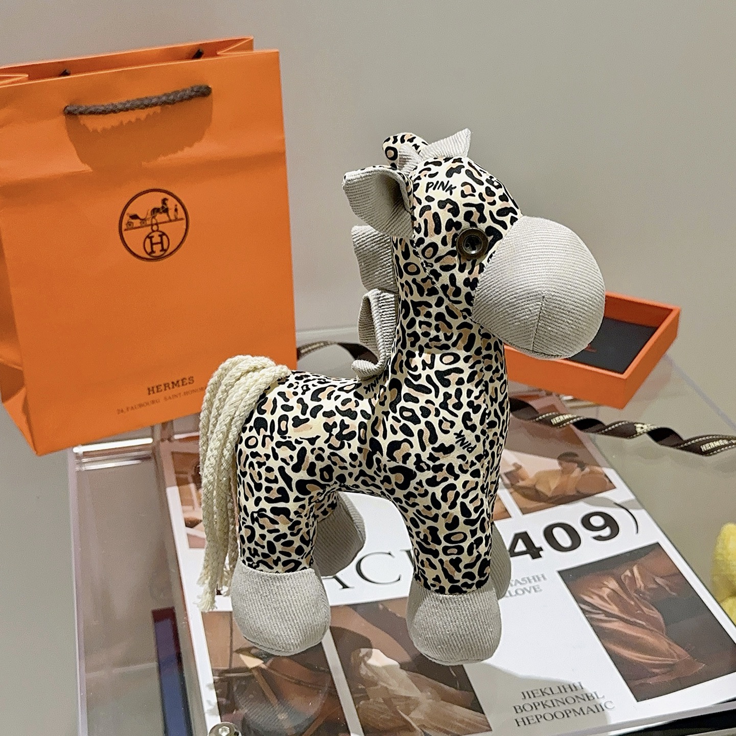 Hermes Hermy Leopard Print Plush Horse Charm pendente Tessuto beige con stampa leopardata nera e marrone chiaro accenti di velluto a coste grigio chiaro coda di cordone intrecciato color crema 25 cm