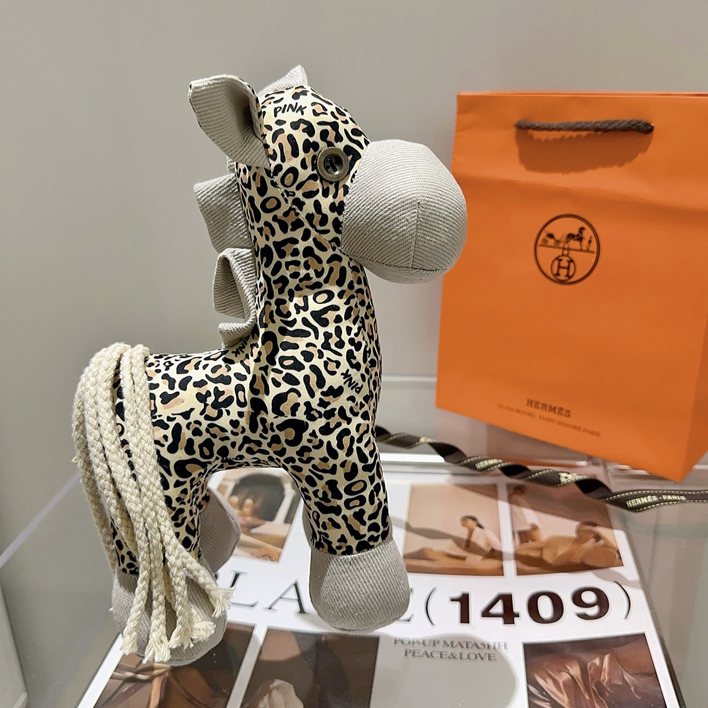 Hermes Hermy Leopard Print Plush Horse Charm pendente Tessuto beige con stampa leopardata nera e marrone chiaro accenti di velluto a coste grigio chiaro coda di cordone intrecciato color crema 25 cm