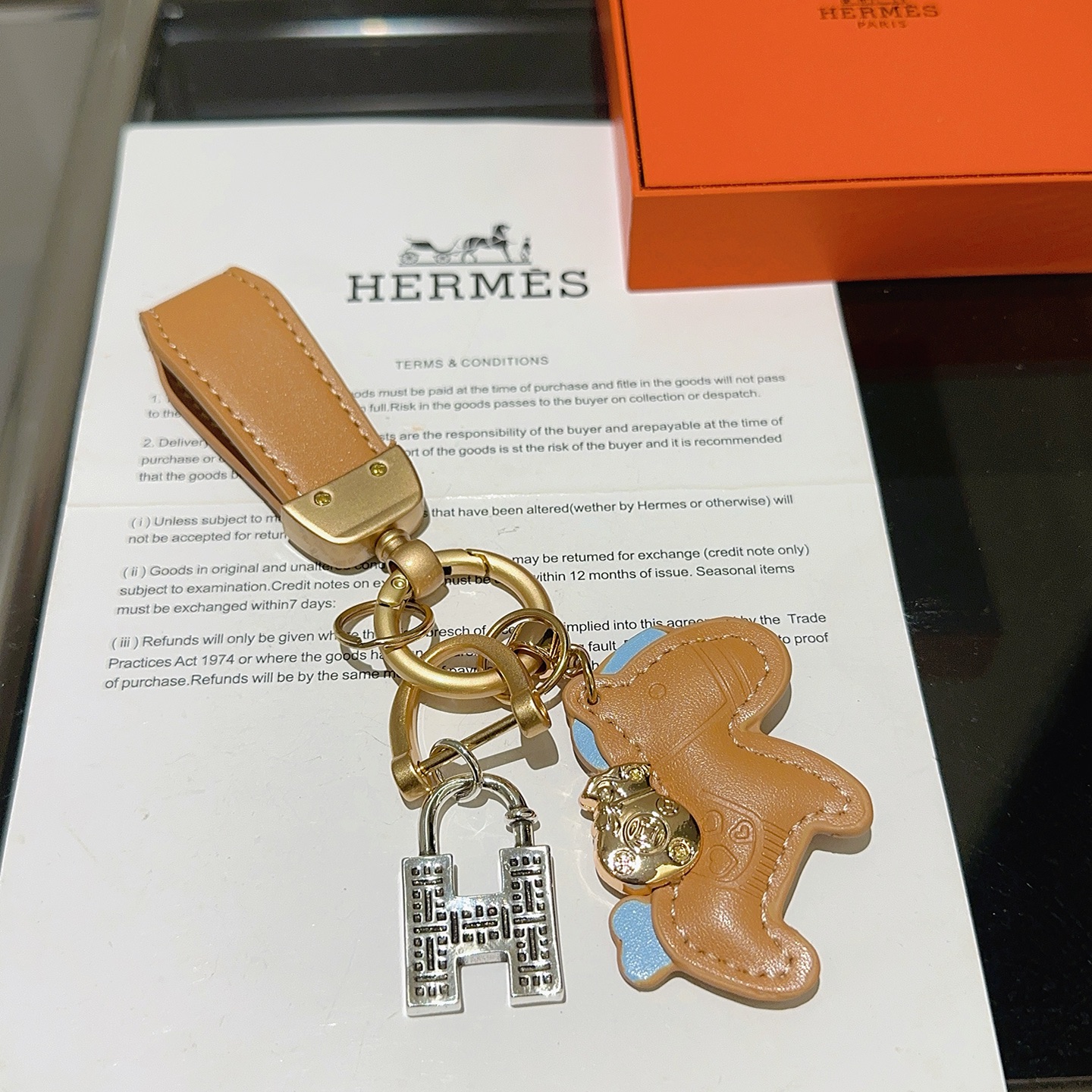 Ciondolo portachiavi Hermes Horse Charm Pelle marrone chiaro con accenti azzurri hardware oro opaco ciondolo con lucchetto H color argento lunghezza totale 10 cm
