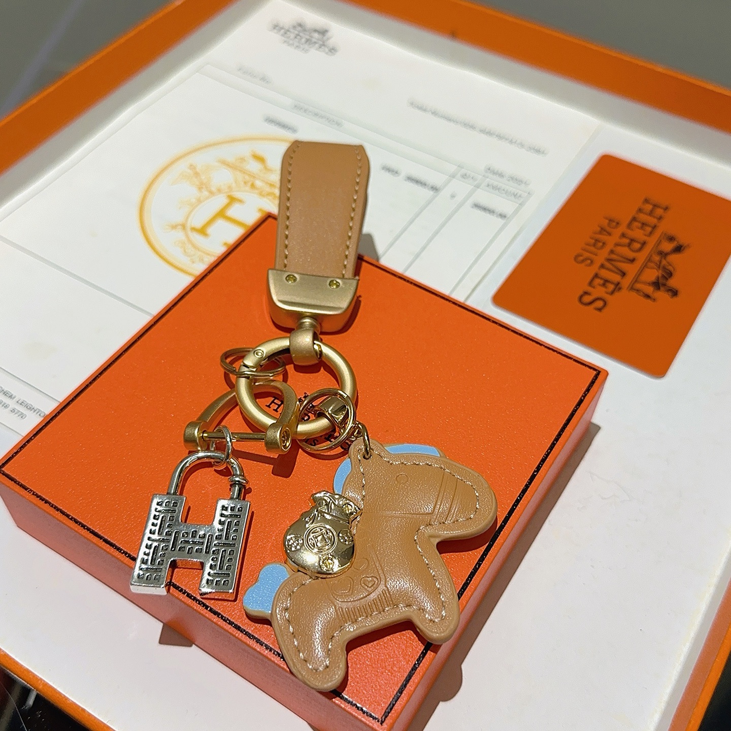 Ciondolo portachiavi Hermes Horse Charm Pelle marrone chiaro con accenti azzurri hardware oro opaco ciondolo con lucchetto H color argento lunghezza totale 10 cm