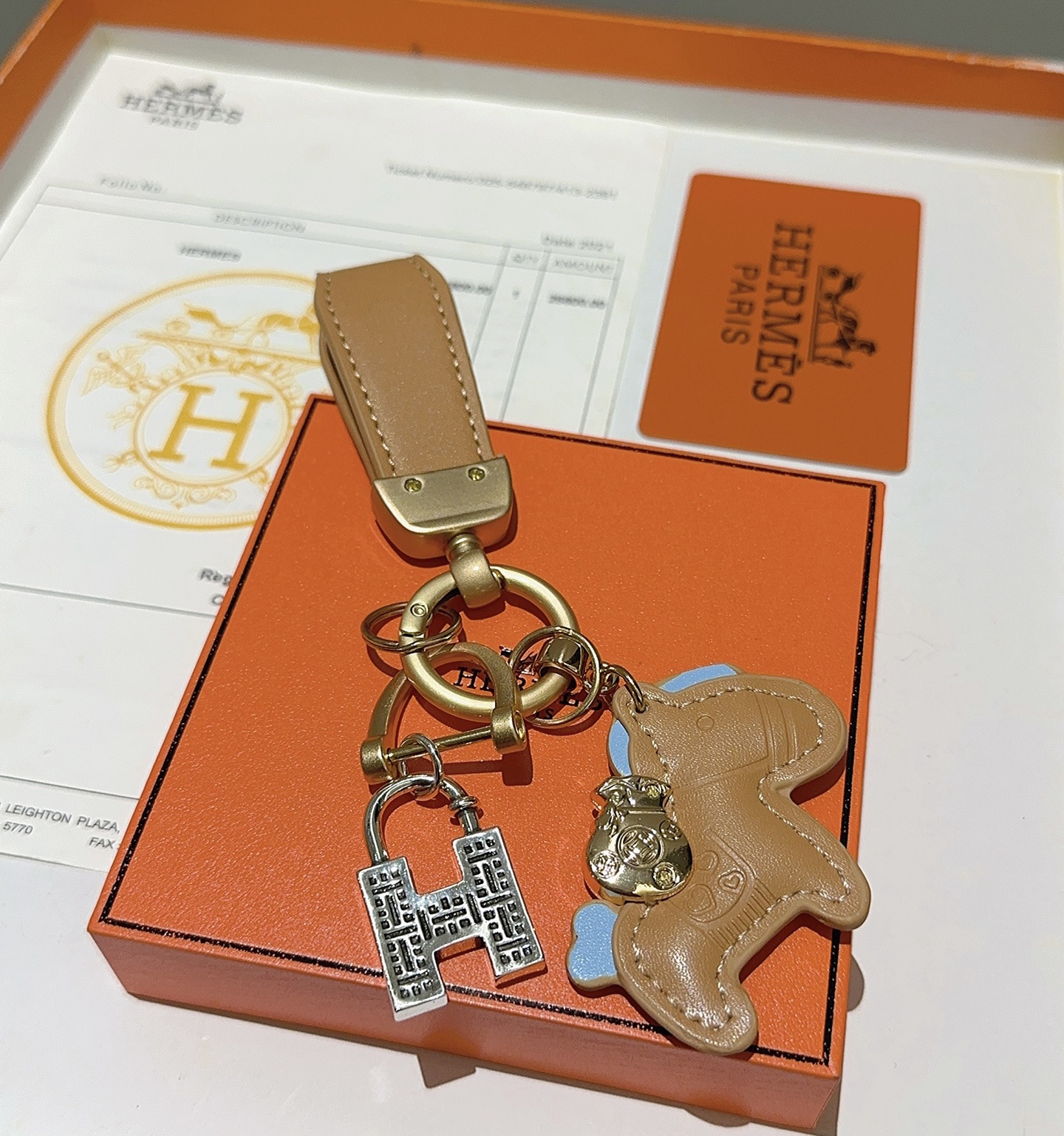 Ciondolo portachiavi Hermes Horse Charm Pelle marrone chiaro con accenti azzurri hardware oro opaco ciondolo con lucchetto H color argento lunghezza totale 10 cm