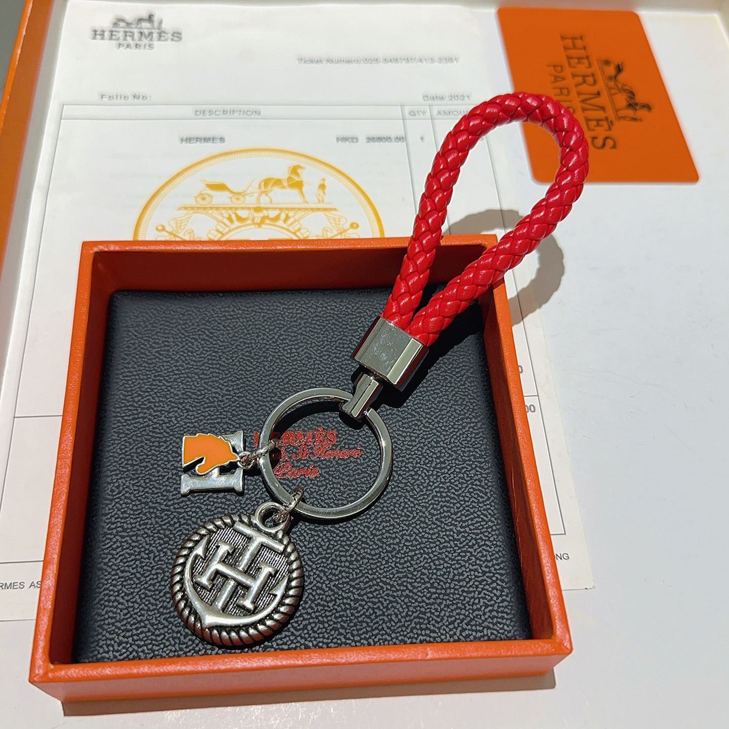 Chaveiro trançado com logotipo Hermes H, pingente de couro trançado vermelho, metal prateado, esmalte laranja, 10 cm de comprimento total