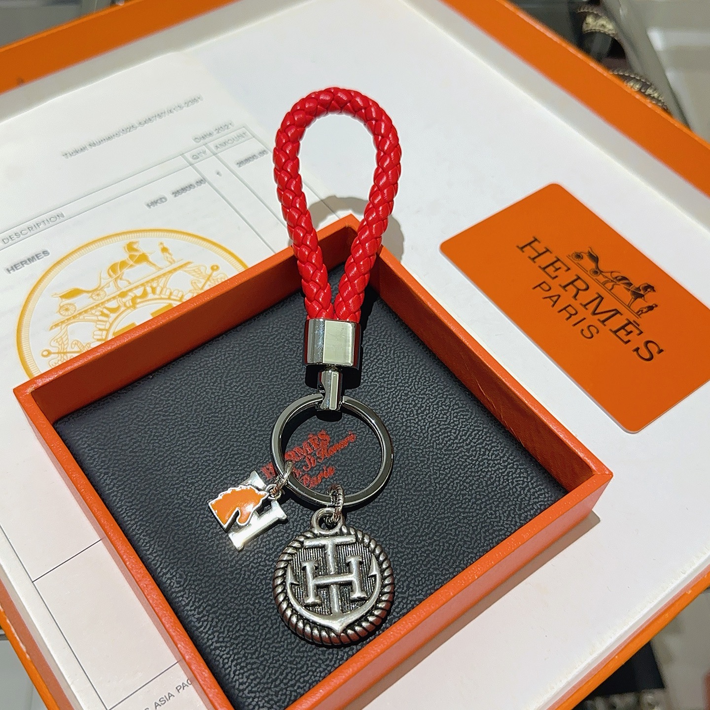 Chaveiro trançado com logotipo Hermes H, pingente de couro trançado vermelho, metal prateado, esmalte laranja, 10 cm de comprimento total