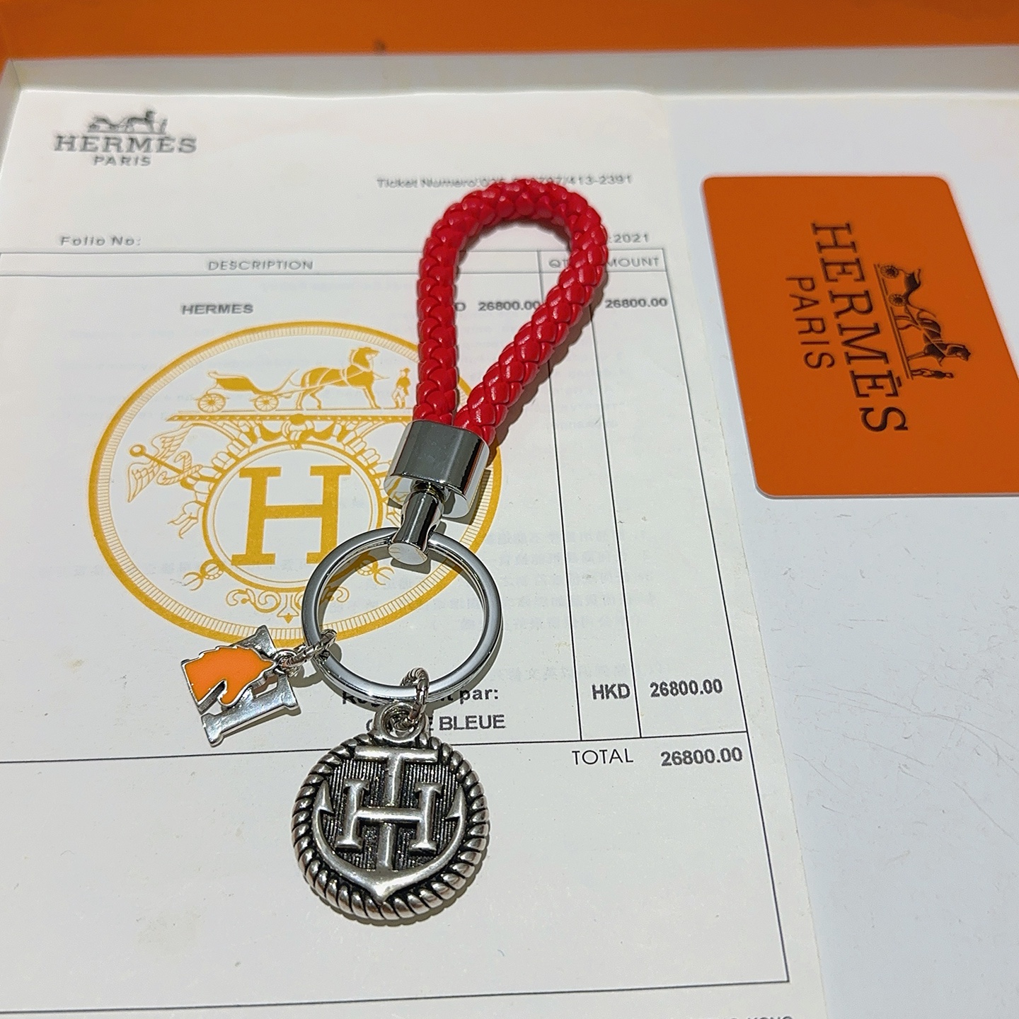 Chaveiro trançado com logotipo Hermes H, pingente de couro trançado vermelho, metal prateado, esmalte laranja, 10 cm de comprimento total