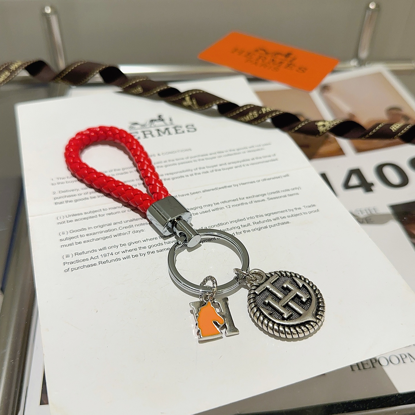 Chaveiro trançado com logotipo Hermes H, pingente de couro trançado vermelho, metal prateado, esmalte laranja, 10 cm de comprimento total