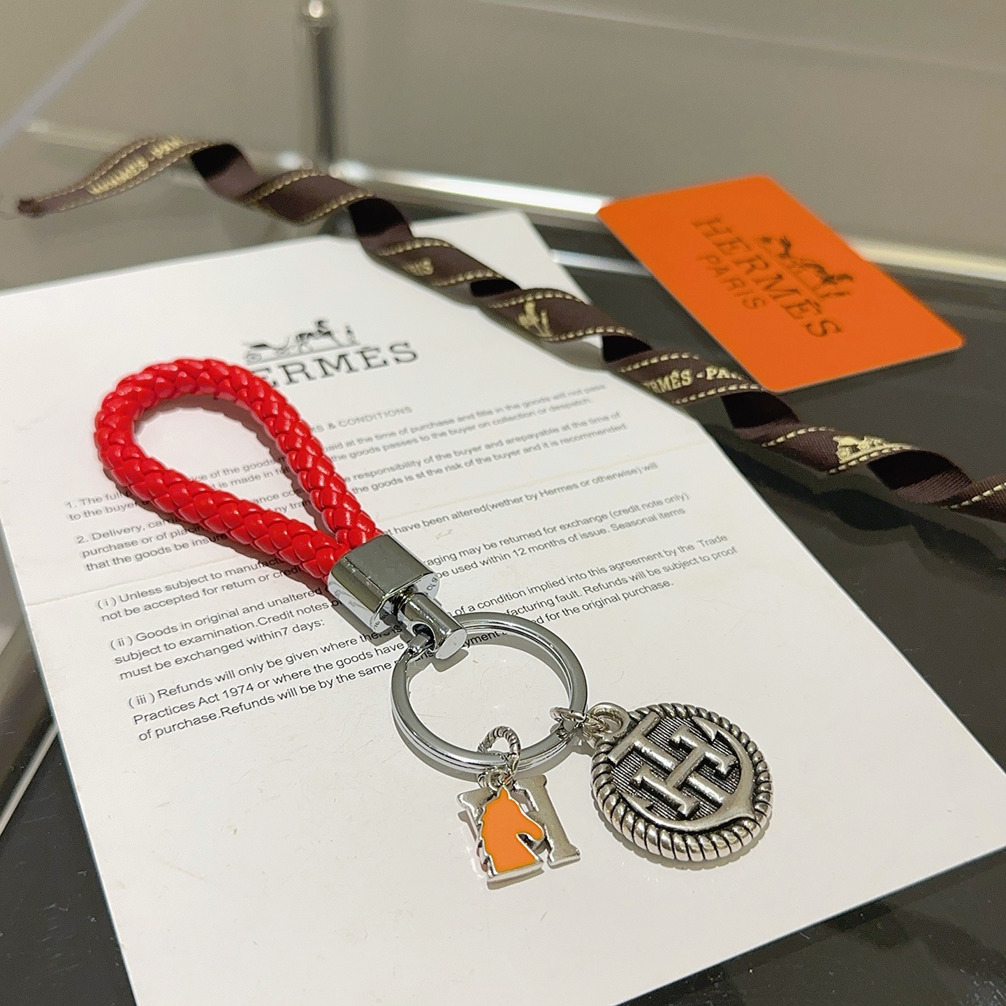 Chaveiro trançado com logotipo Hermes H, pingente de couro trançado vermelho, metal prateado, esmalte laranja, 10 cm de comprimento total