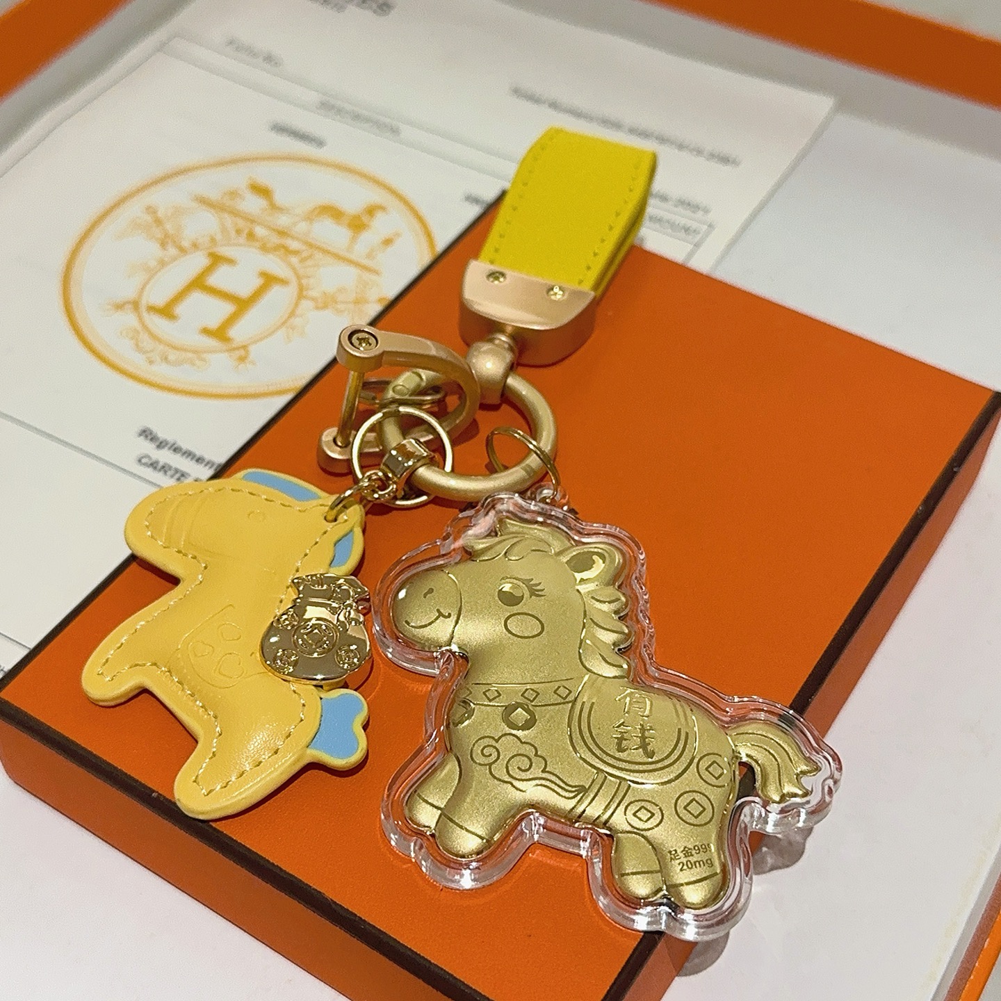 Hermes Rodeo Horse Lucky Money Key Charm Ciondolo Hardware in oro opaco Pelle gialla con accenti azzurri Ciondolo a cavallo in lamina d'oro in involucro acrilico trasparente Lunghezza totale 10 cm