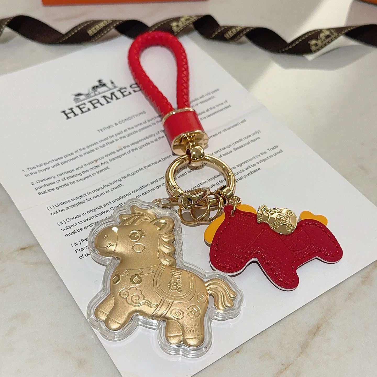 Hermes Lucky Horse Charm Portachiavi Ciondolo Portachiavi in ​​pelle intrecciata rossa in metallo color oro Ciondolo cavallo in pelle rossa Ciondolo cavallo dorato con involucro protettivo trasparente Dettagli accenti gialli Lunghezza totale 10 cm