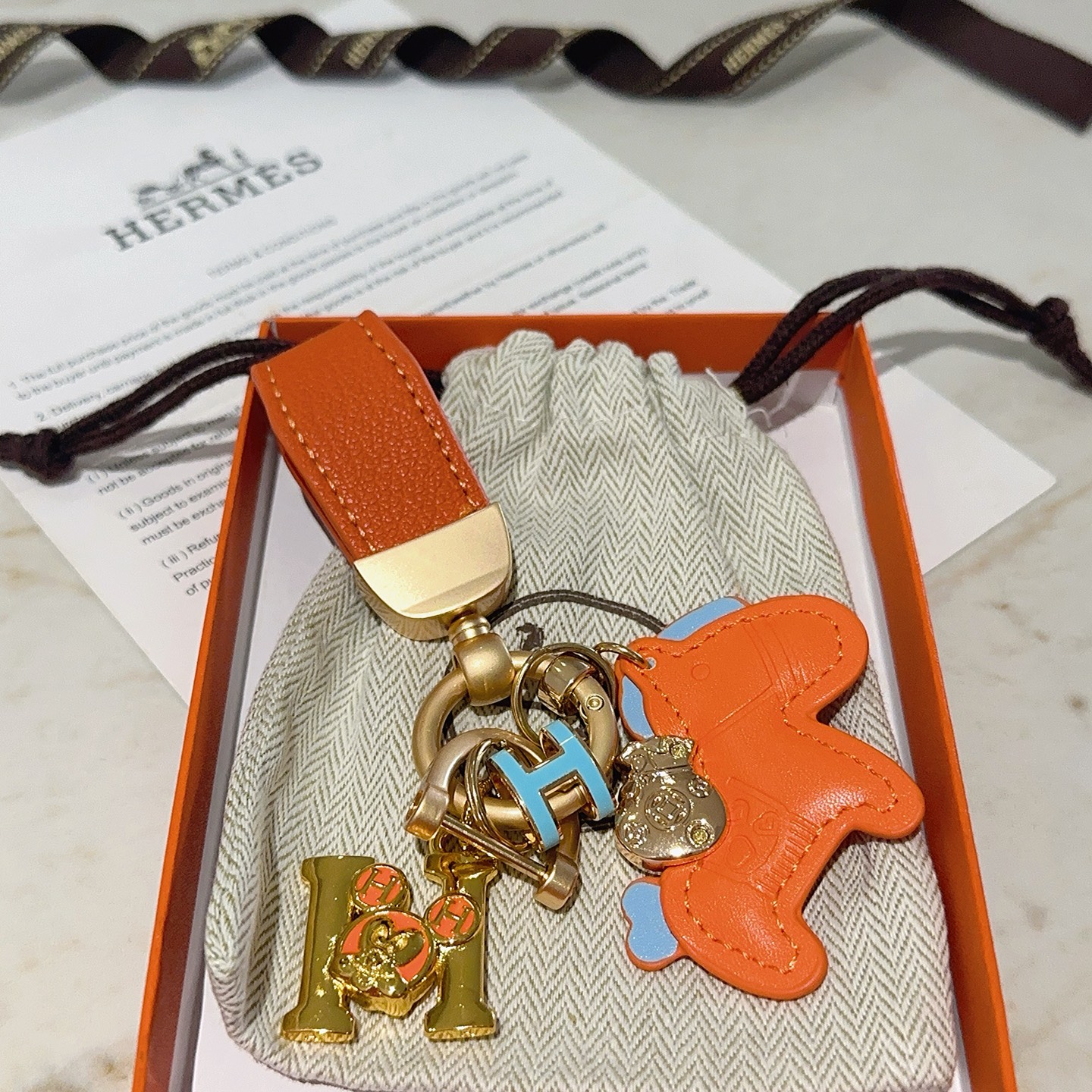 Ciondolo portachiavi Hermes Rodeo Horse Charm Pelle arancione con accenti azzurri Hardware in metallo color oro, lunghezza totale 10 cm