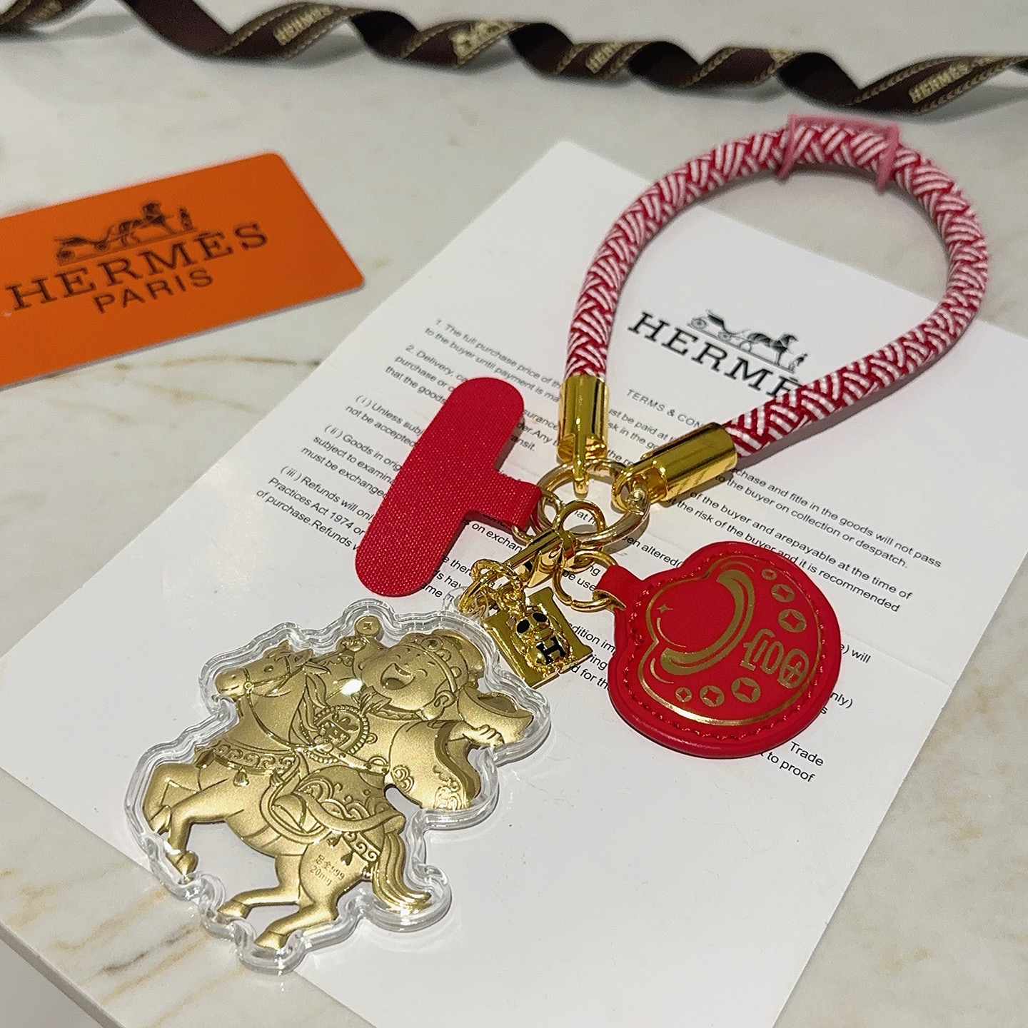 Hermes Get Rich God of Wealth on Horse Key Ciondolo con ciondolo Cordone intrecciato rosso e bianco metallo color oro pelle rossa rivestimento in acrilico trasparente dettagli in lamina d'oro Lunghezza del passante da polso di 18 cm