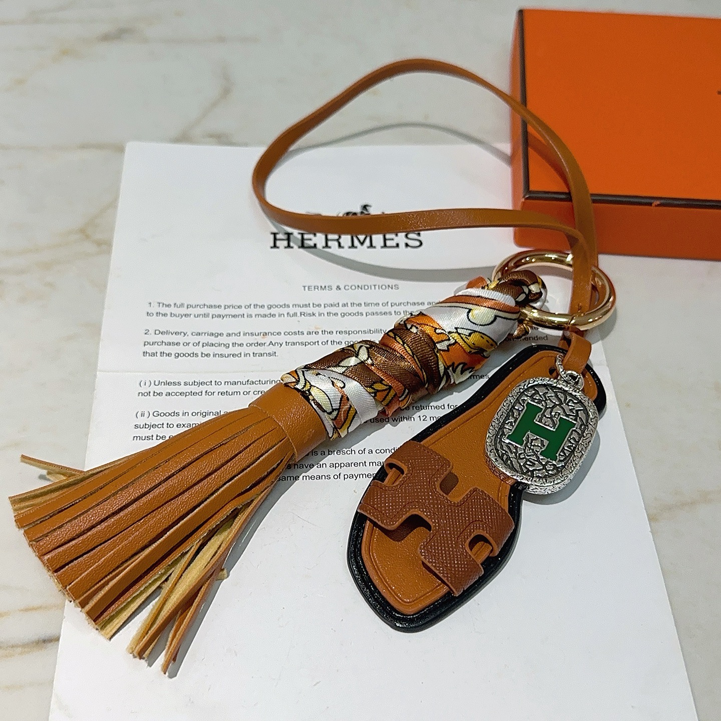 Hermes Oran Sandalo Borsa con nappa Ciondolo con ciondolo Metallo color oro Pelle marrone chiaro Seta stampata multicolore Hardware color argento con dettaglio H in smalto verde Finiture in pelle nera Lunghezza cinturino 18 cm