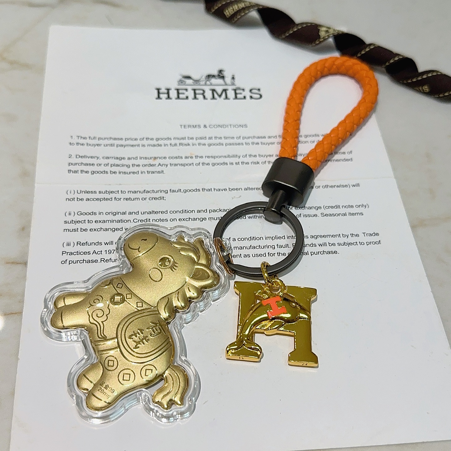 Hermes Lucky Horse H Logo Portachiavi Ciondolo con ciondolo Pelle intrecciata arancione Hardware in canna di fucile Ciondoli in metallo color oro con accento H arancione Rivestimento in acrilico trasparente 10 cm Cinturino intrecciato 4 cm