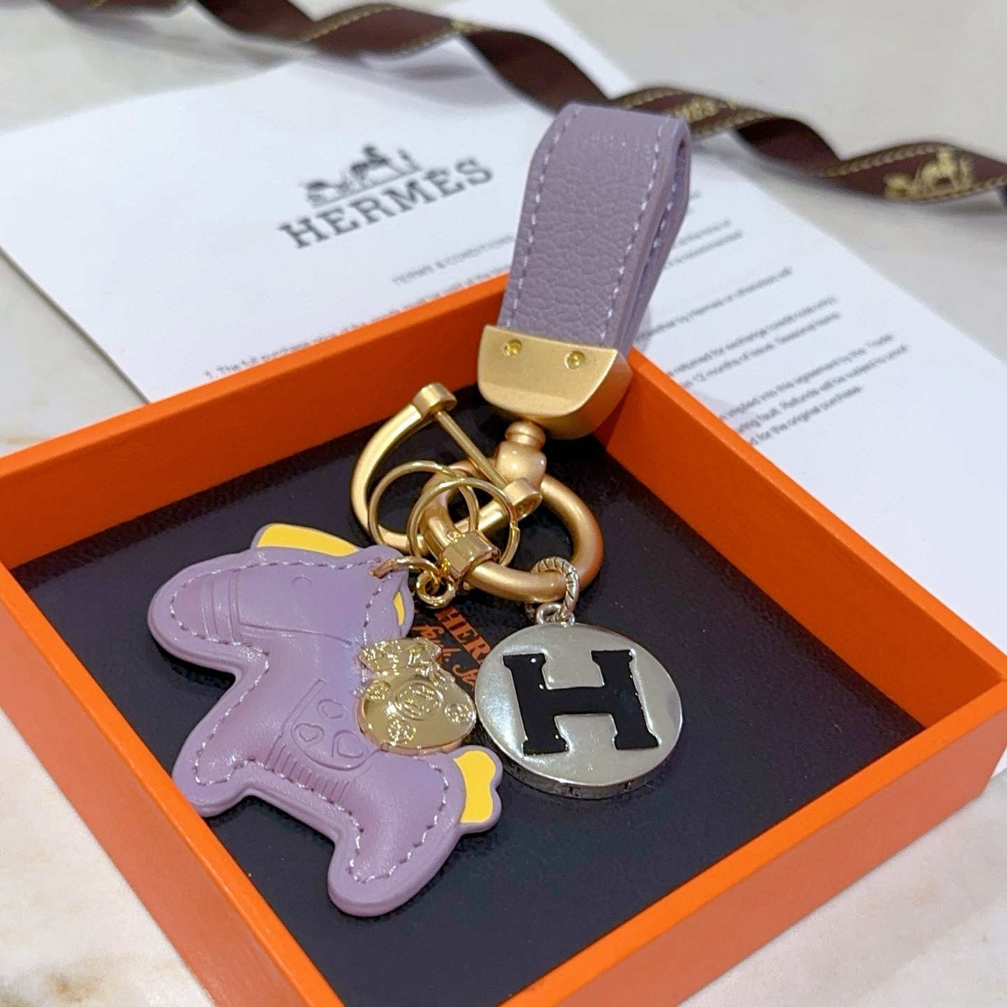 Ciondolo chiave Hermes Rodeo Horse H Logo ciondolo in metallo color oro opaco pelle lavanda accento in pelle gialla metallo argentato con logo H smaltato nero lunghezza totale 10 cm